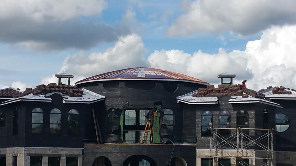 A large house under construction with a blue sky and clouds in the background.