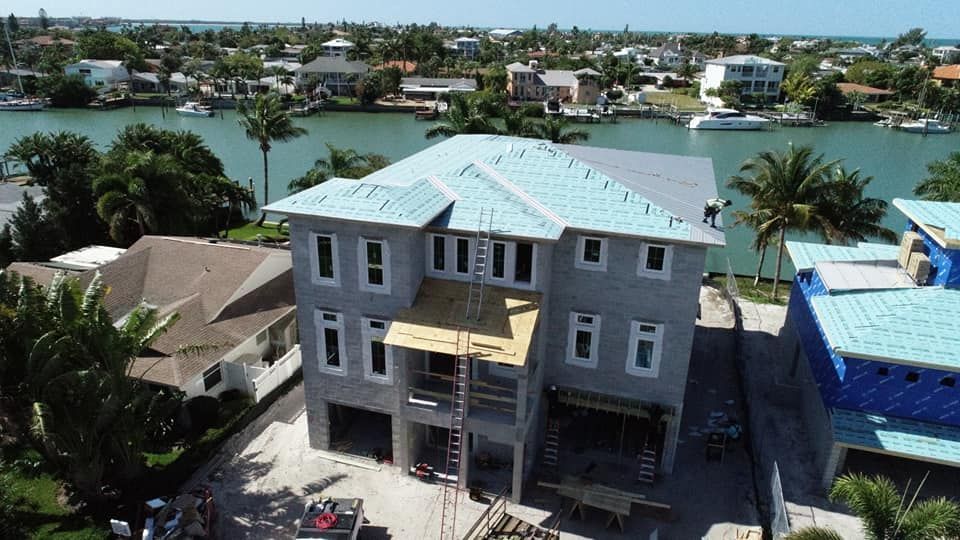 An aerial view of a house under construction next to a body of water.