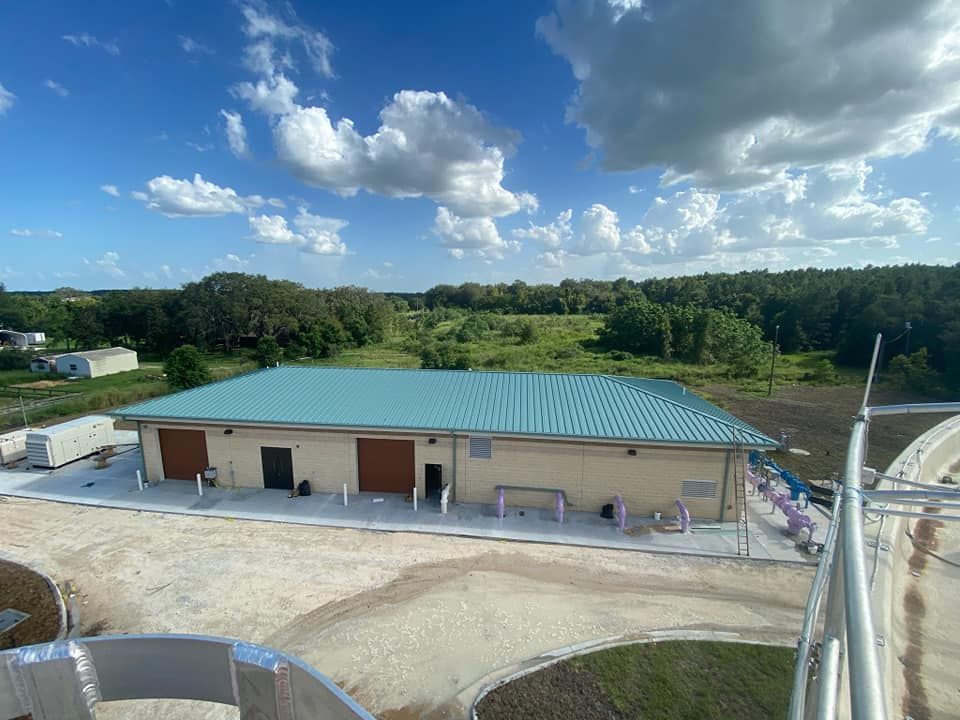 An aerial view of a building with a green roof surrounded by trees.