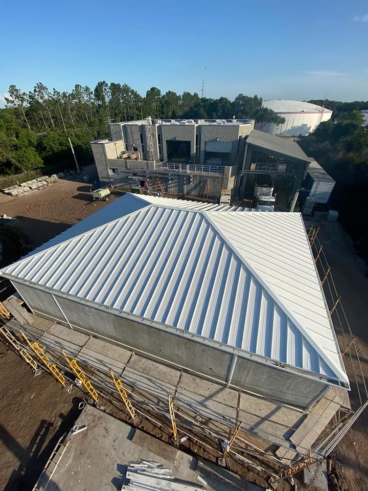 An aerial view of a building under construction with a white roof