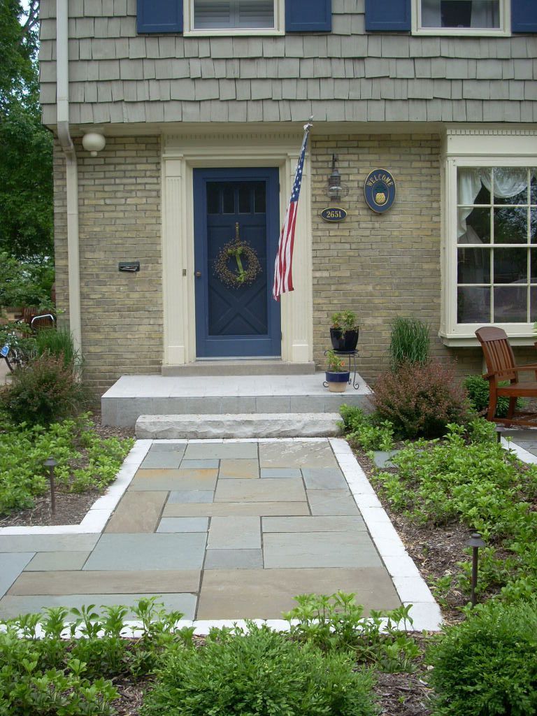 Blue front door with wreath and American flag. Stone walkway leads to the entrance.