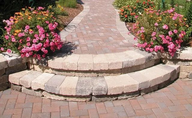 Brick pathway and steps with pink flowers bordering the path.
