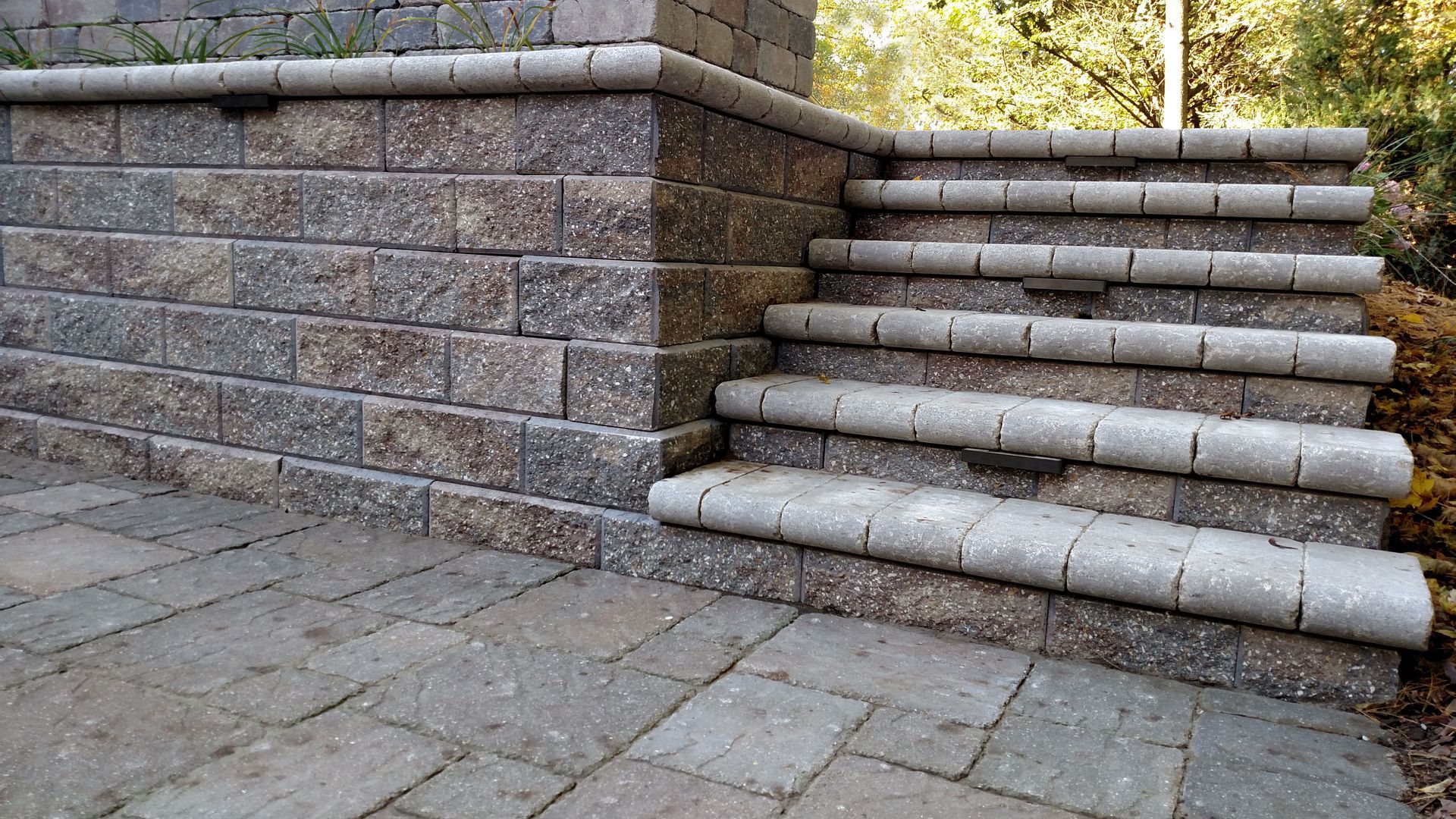 Stone steps and retaining wall leading up to a higher level; grey and brown brick.