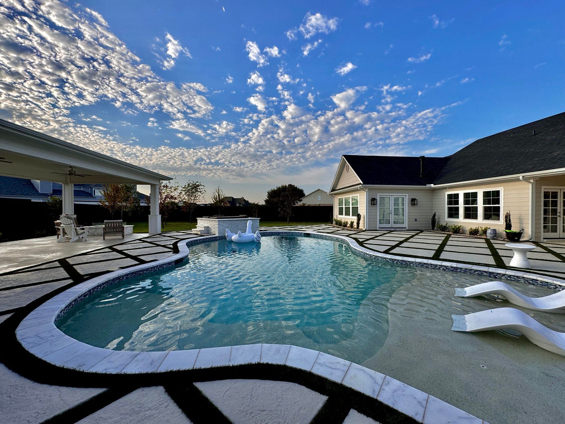 A large swimming pool is in the backyard of a house.