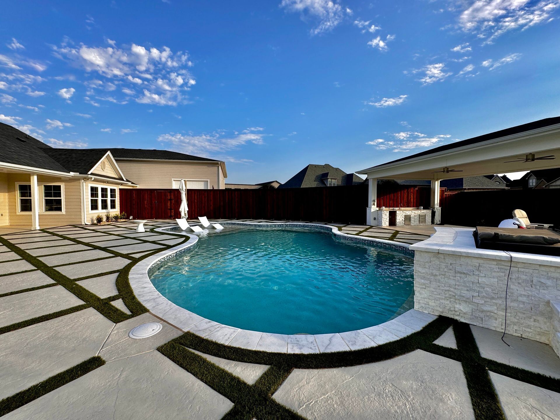 A large swimming pool is in the backyard of a house.