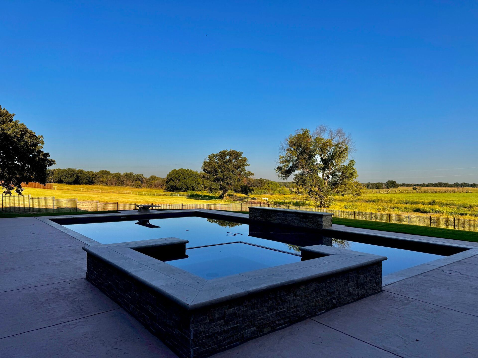 A large swimming pool with a view of a field and trees