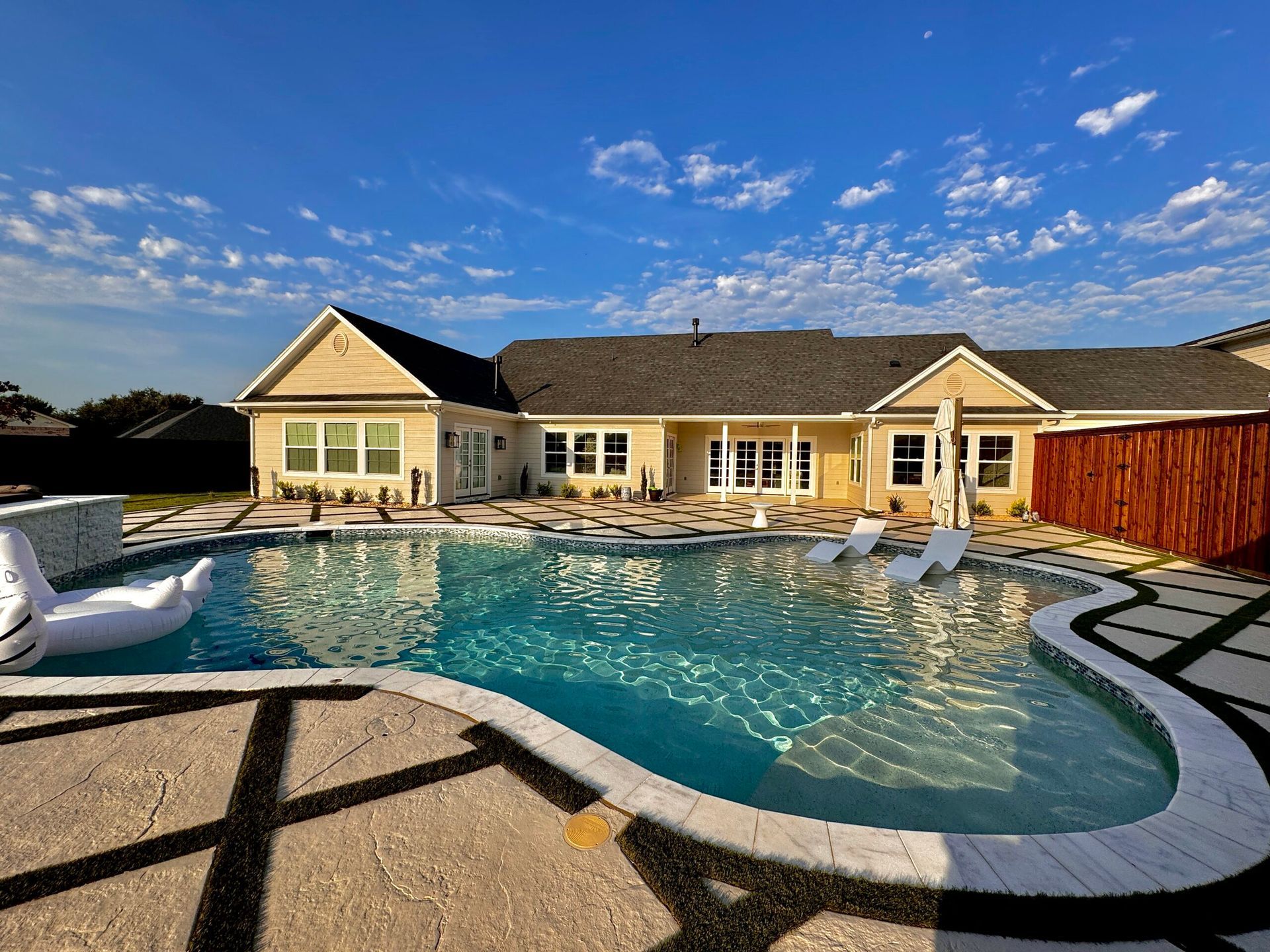 A large swimming pool is in the backyard of a house.