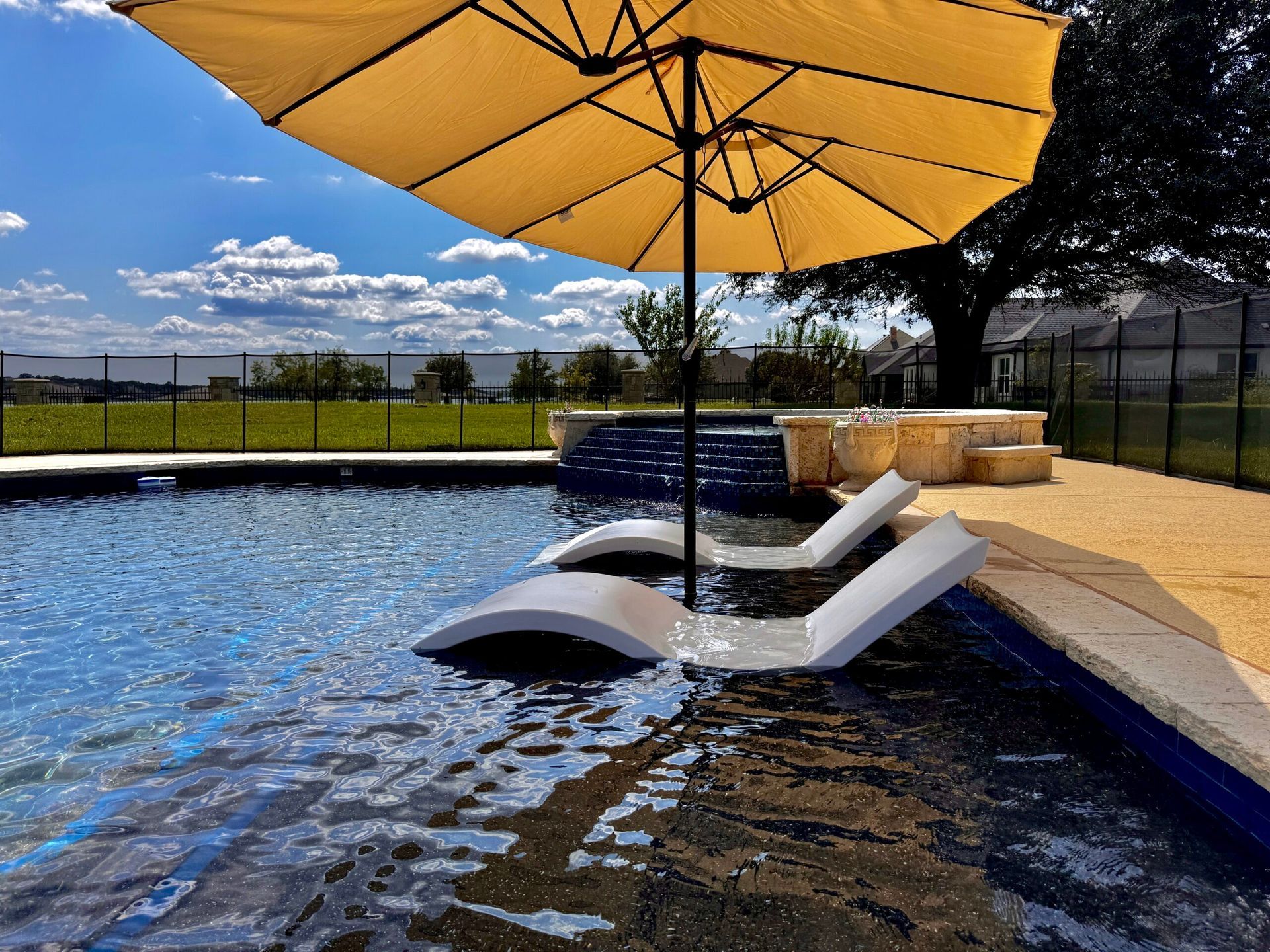 A swimming pool with a yellow umbrella and lounge chairs