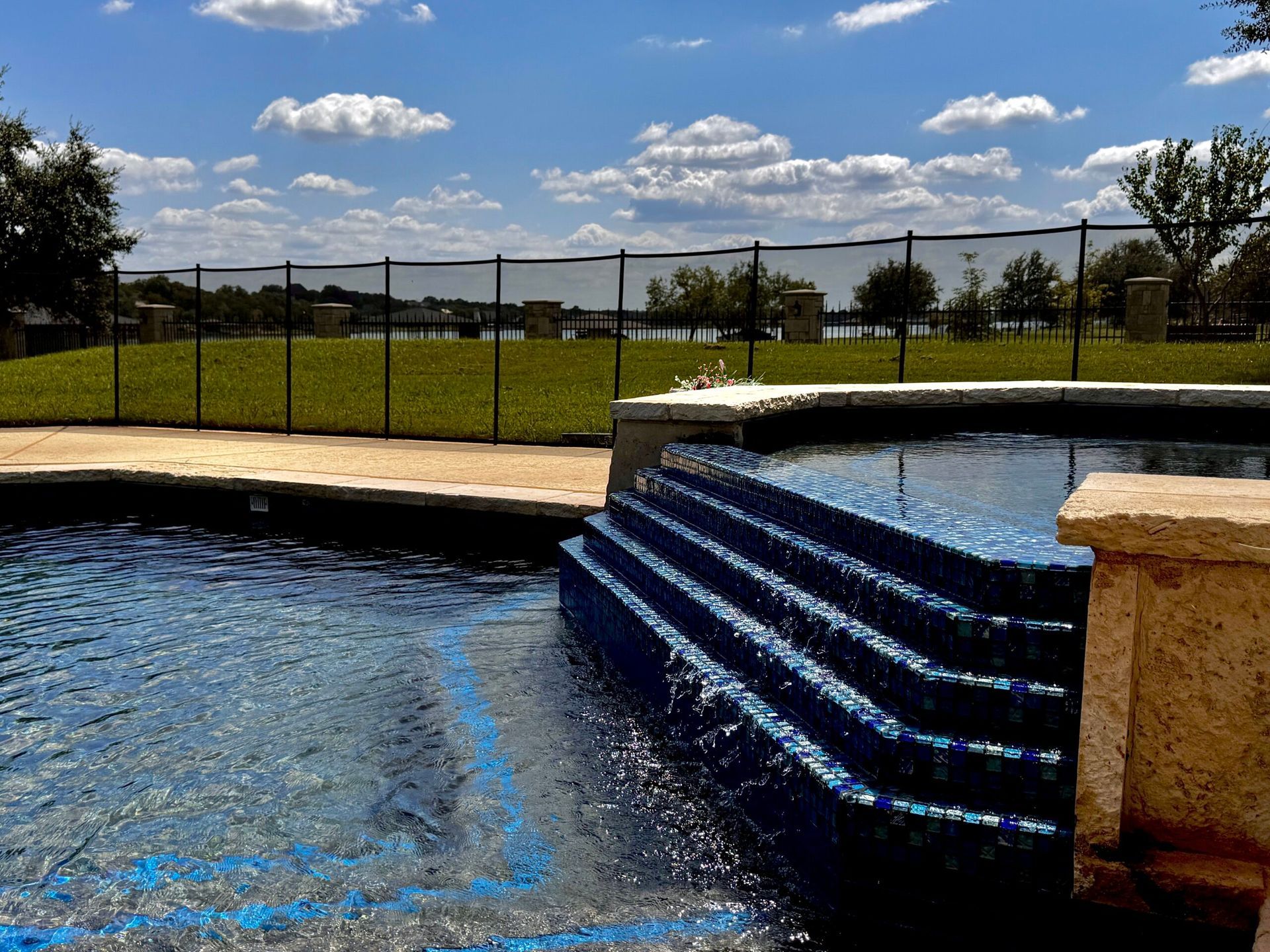 A swimming pool with blue stairs and a fence around it