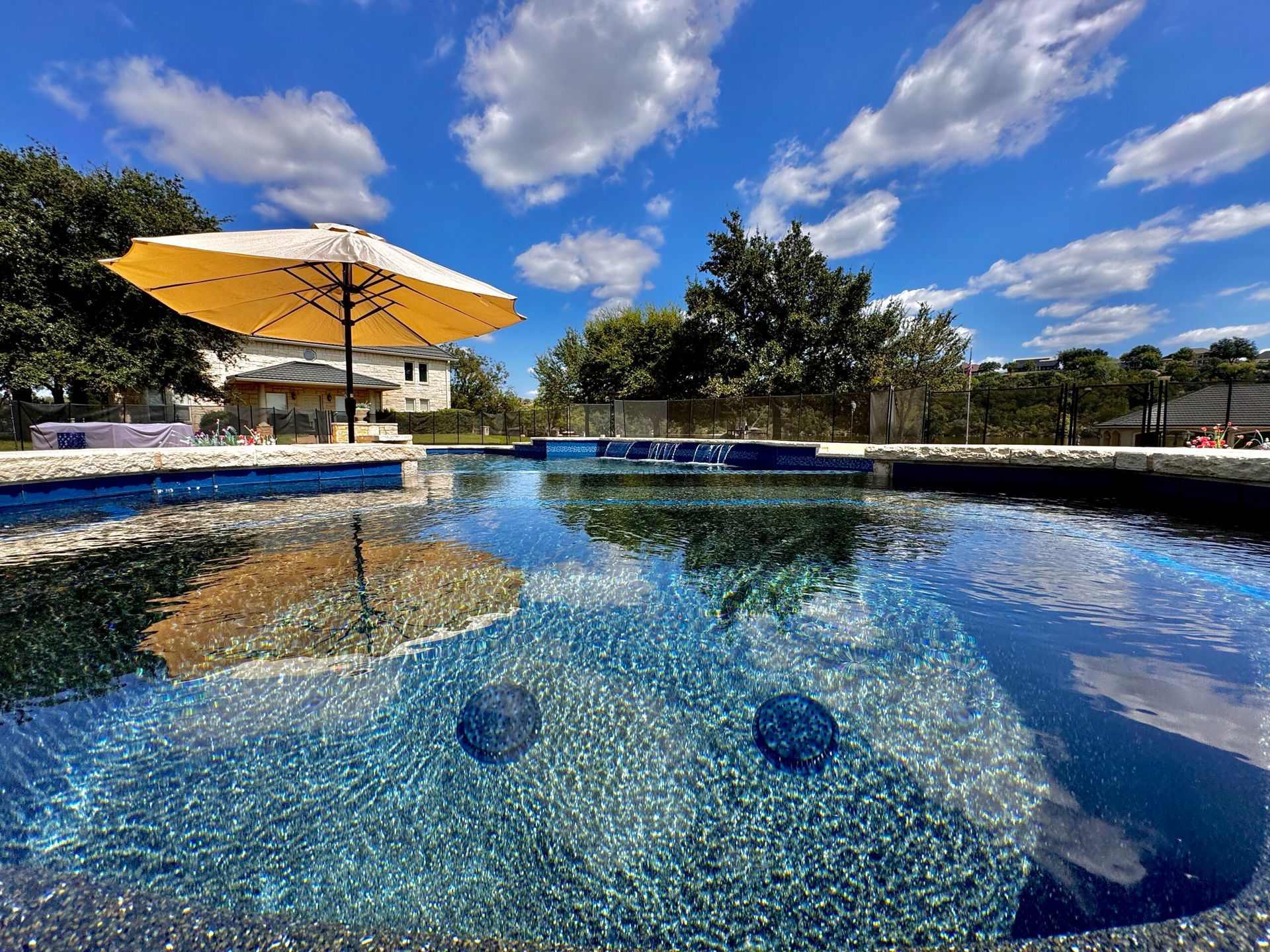 A large swimming pool with a yellow umbrella in the middle of it.