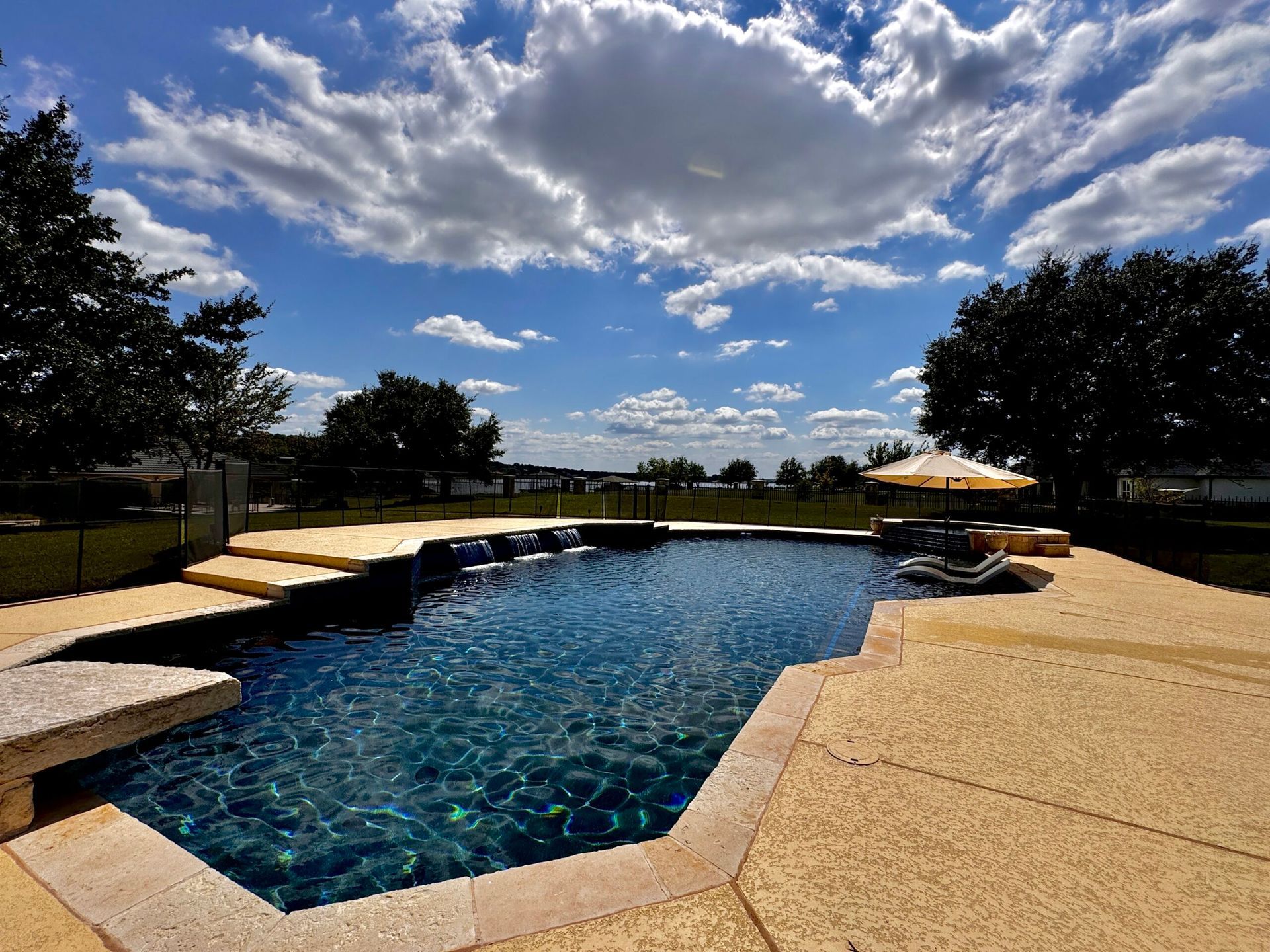 A large swimming pool with a blue sky and clouds in the background