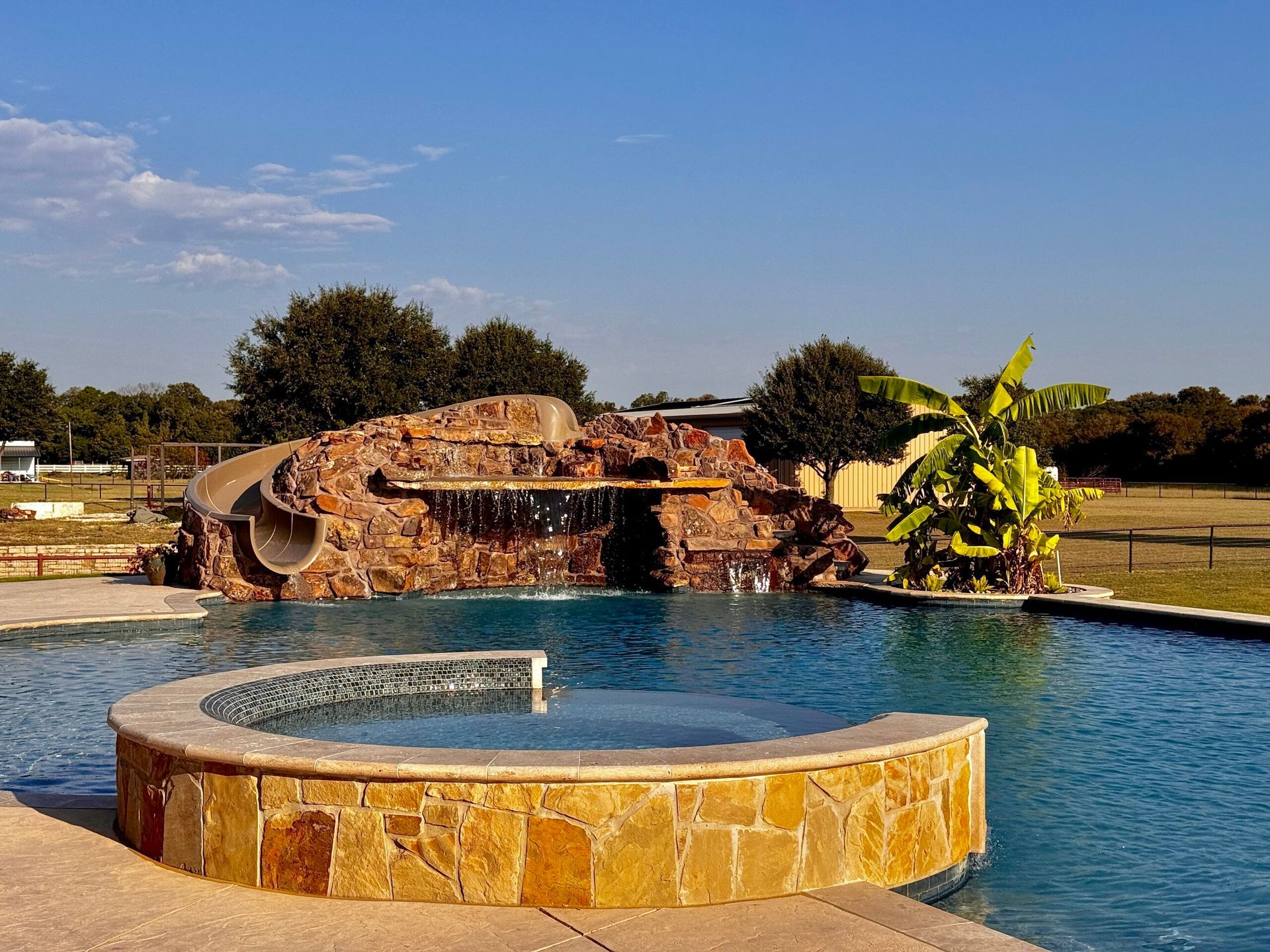 A large swimming pool with a water slide in the background