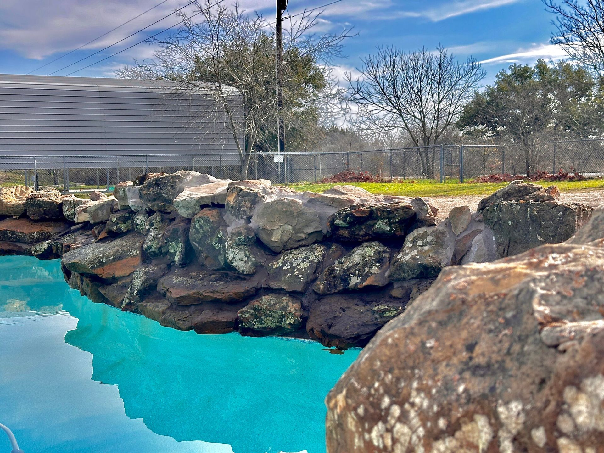 A swimming pool surrounded by rocks and trees on a sunny day
