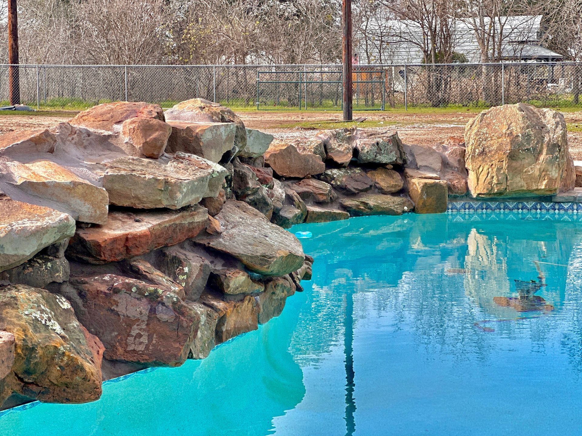 A large swimming pool surrounded by rocks and trees.