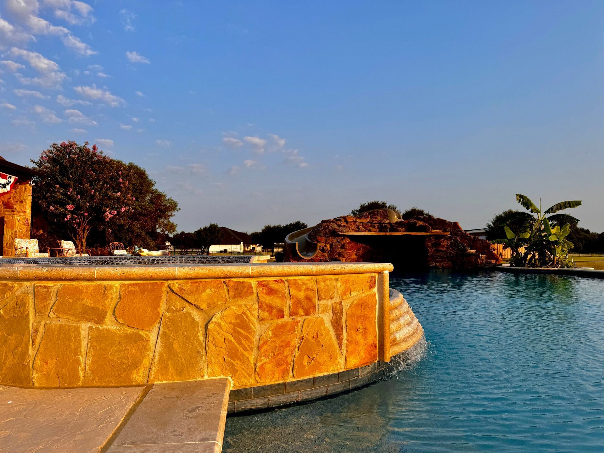 A large swimming pool with a stone wall surrounding it