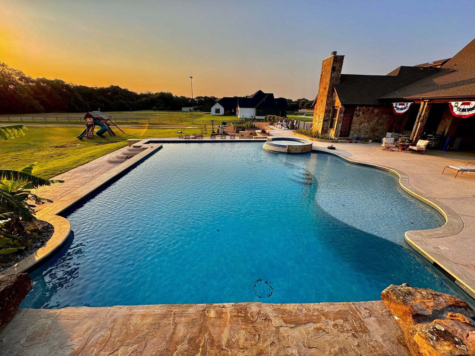 There is a large swimming pool in the backyard of a house.