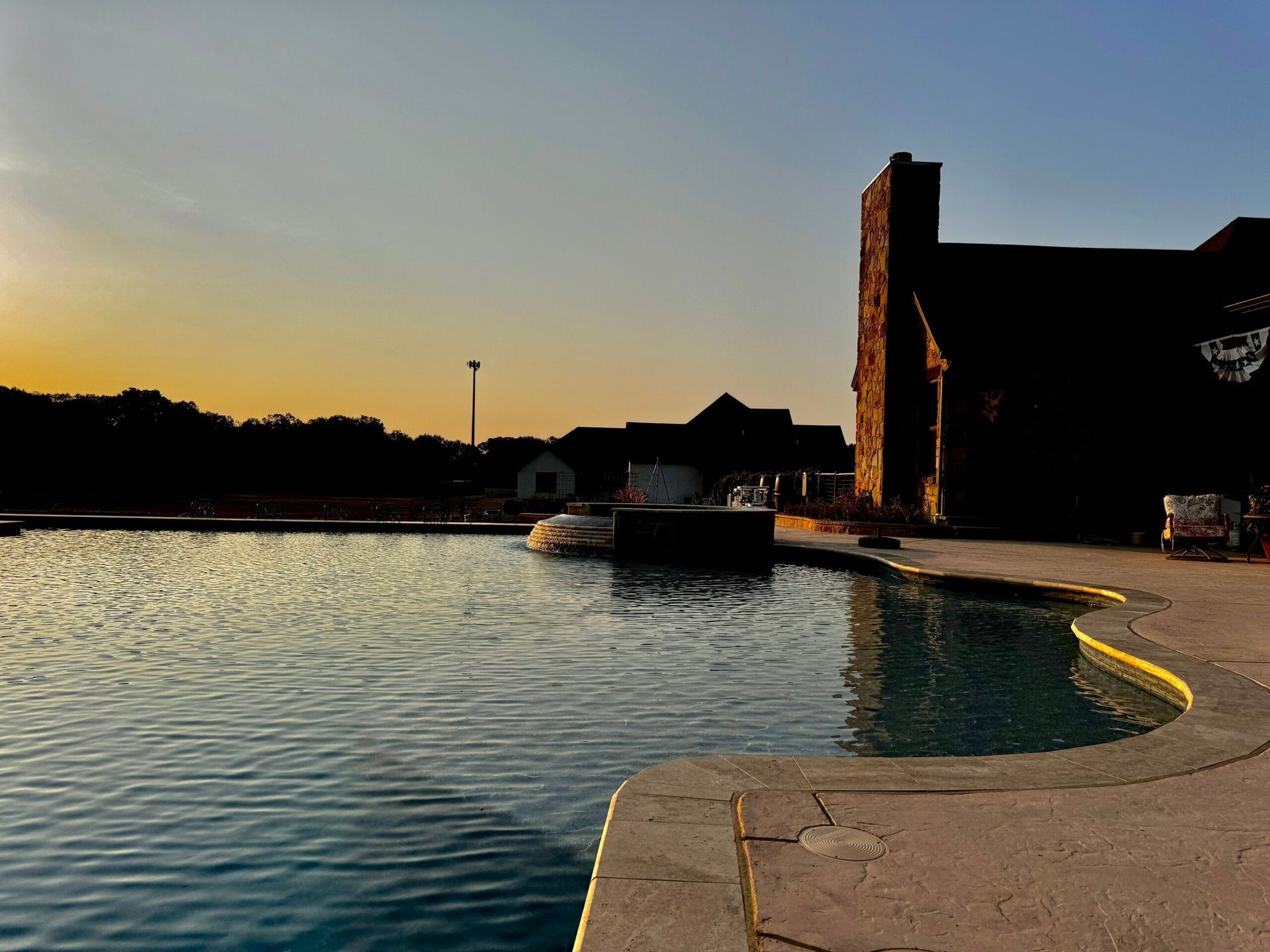 A large swimming pool with a house in the background at sunset