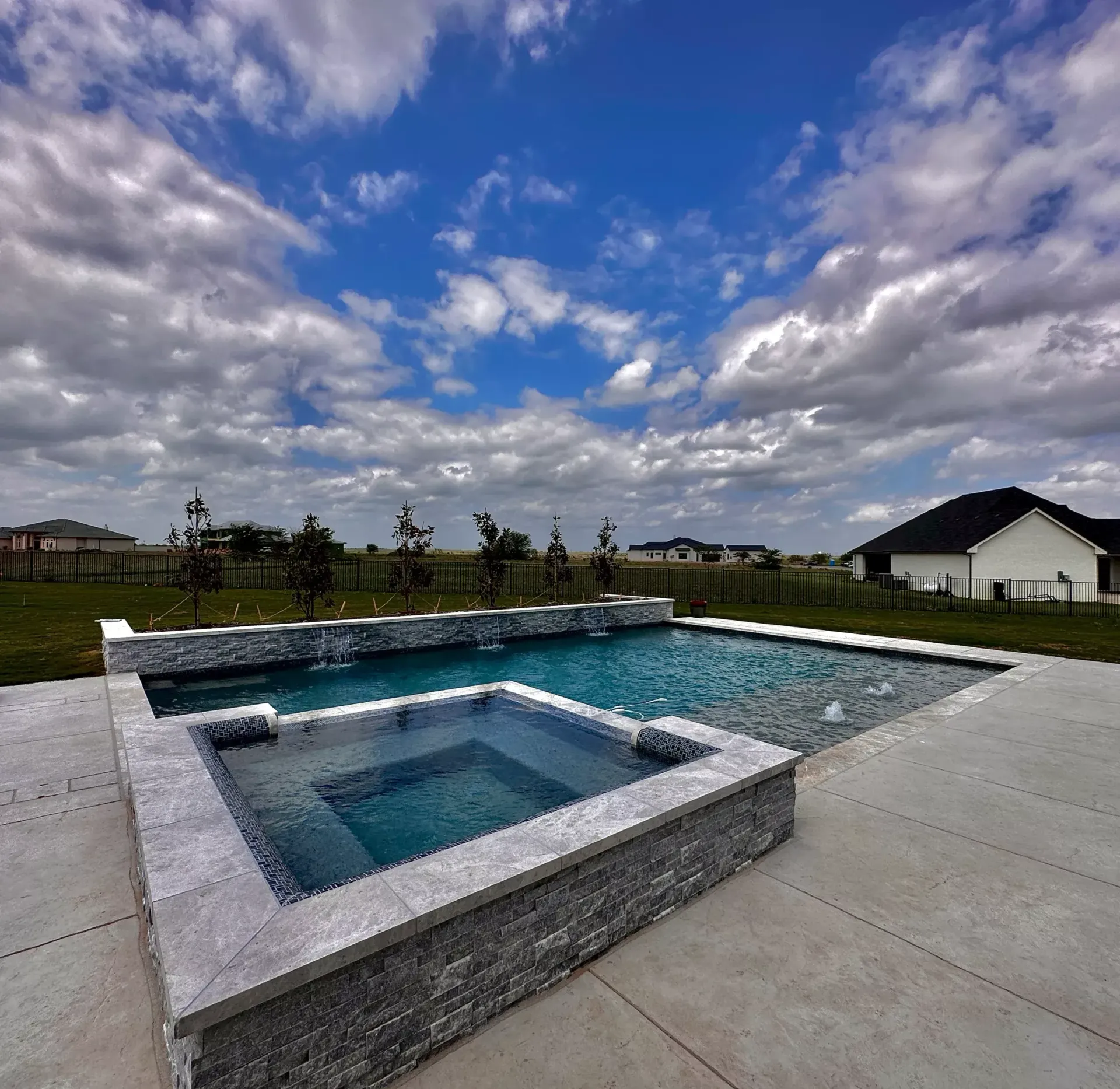 A large swimming pool with a hot tub in the middle
