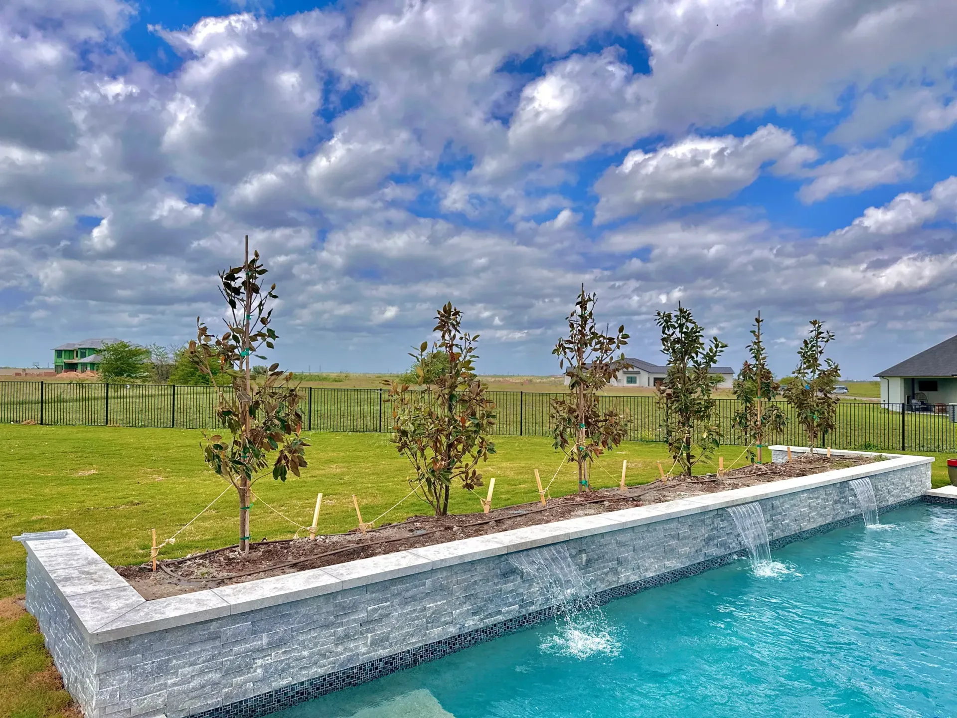A swimming pool with a waterfall and trees in the background.