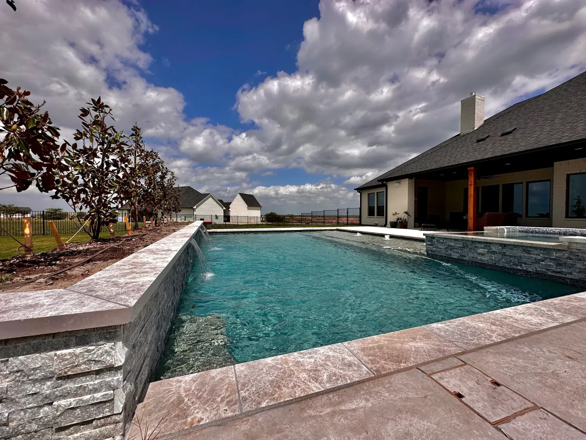 A large swimming pool is in front of a house on a cloudy day.