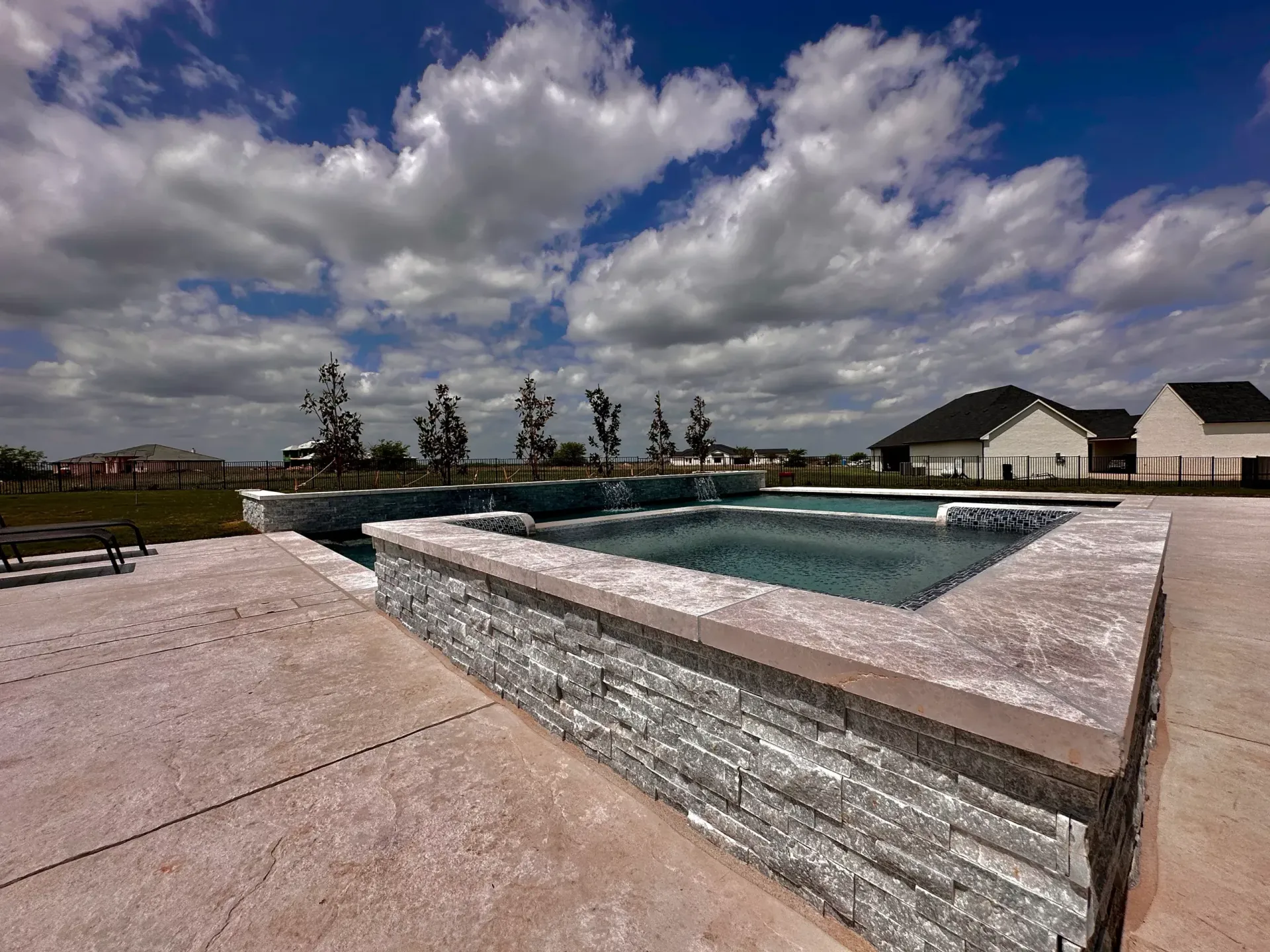 There is a large swimming pool in the backyard of a house.