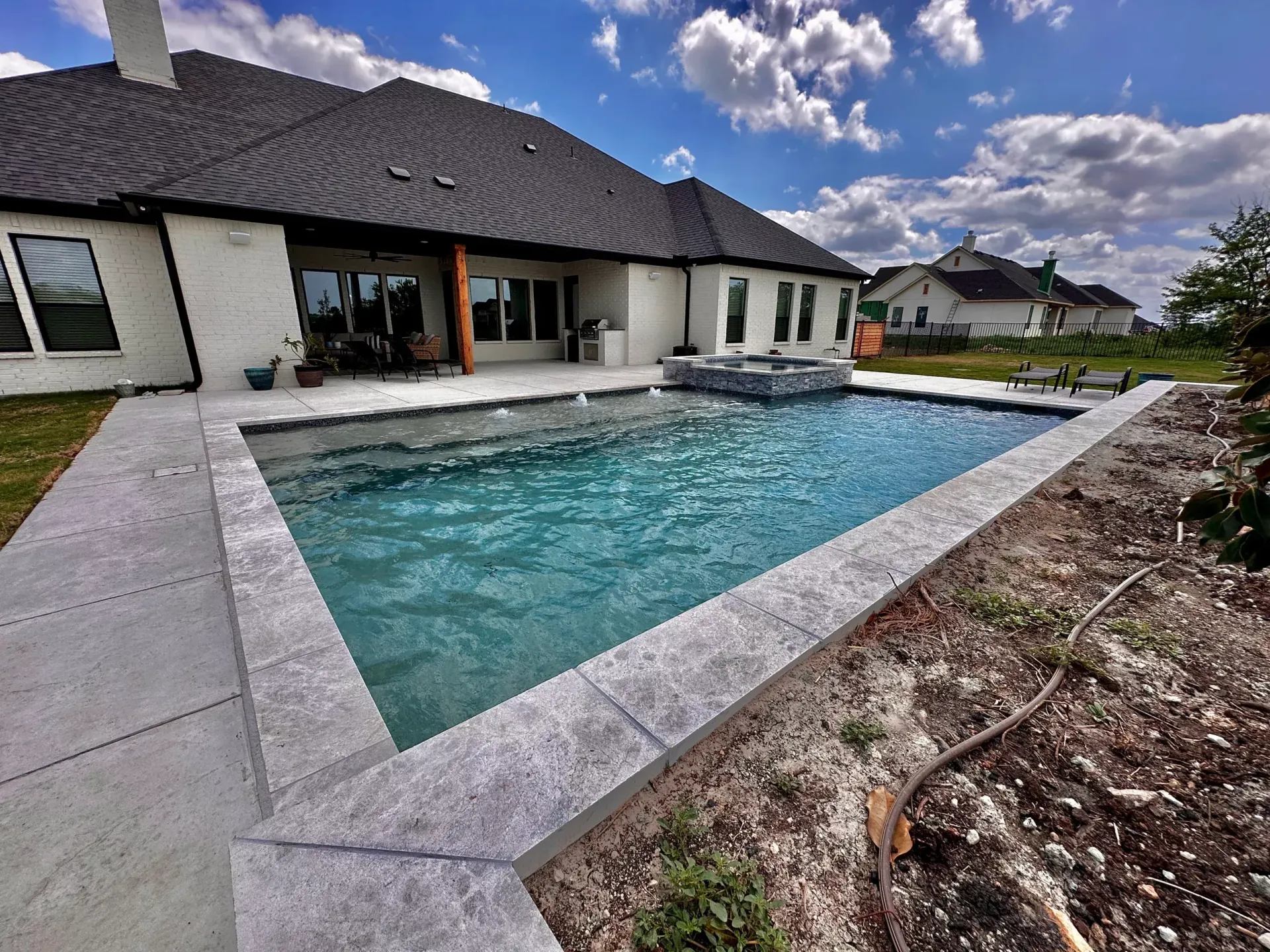 A large swimming pool is in the backyard of a house.