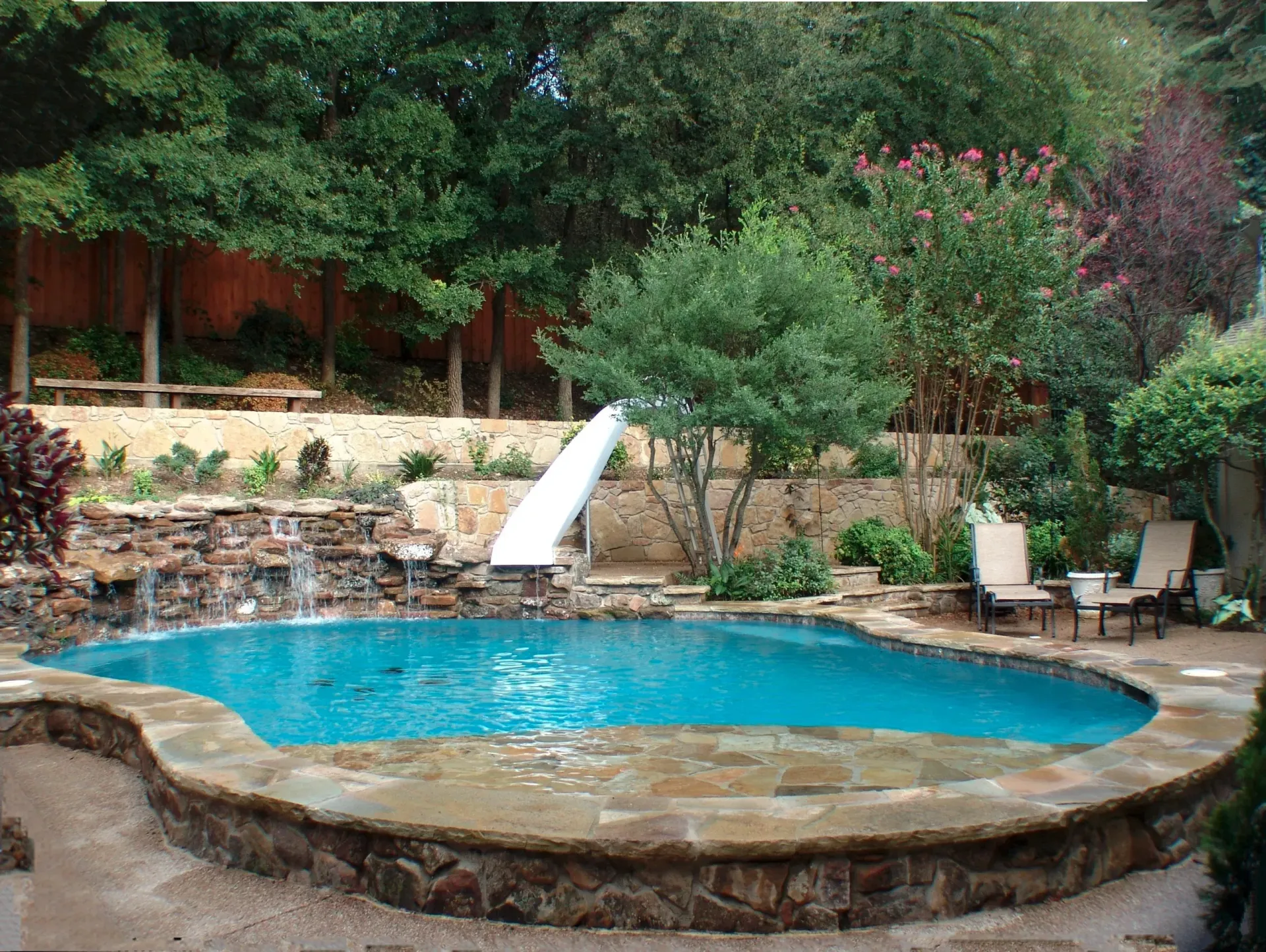 A large swimming pool with a water slide in the backyard