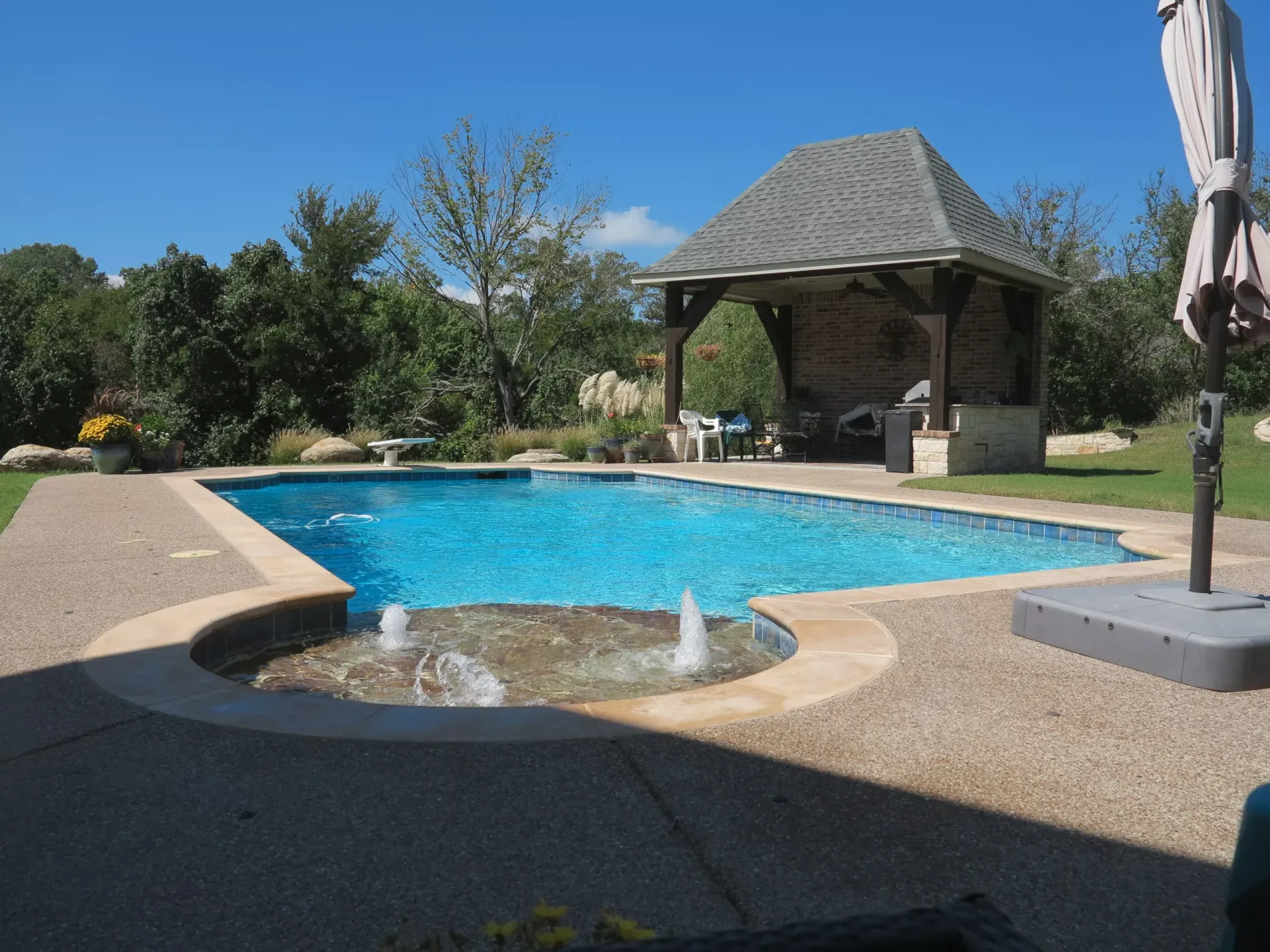 A large swimming pool with a gazebo in the background