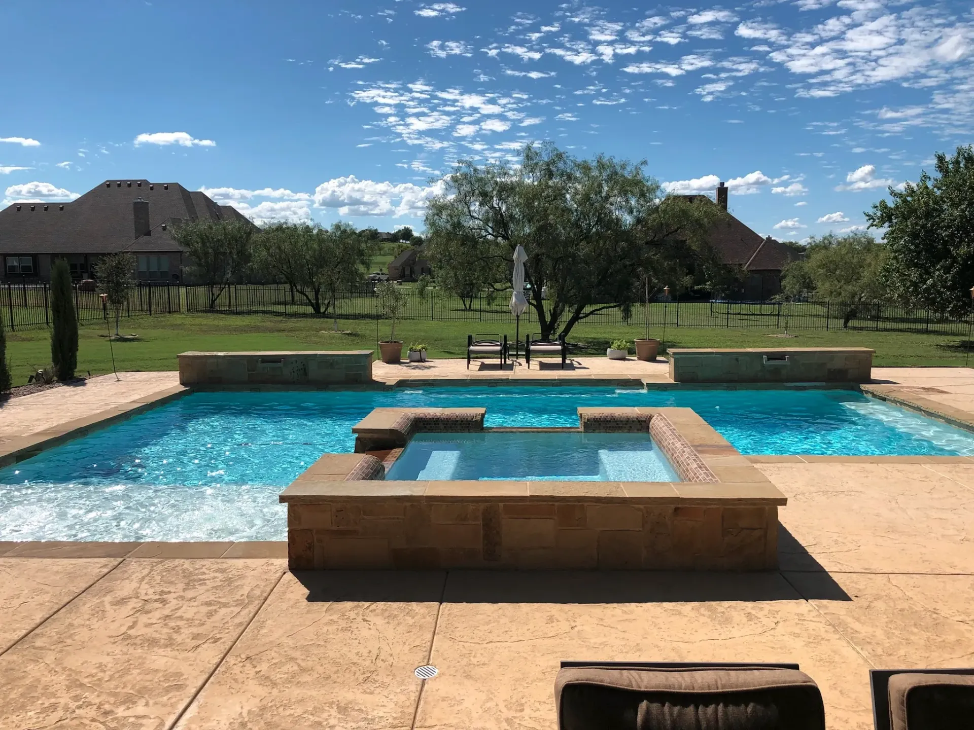 A large swimming pool with a hot tub in the middle of it