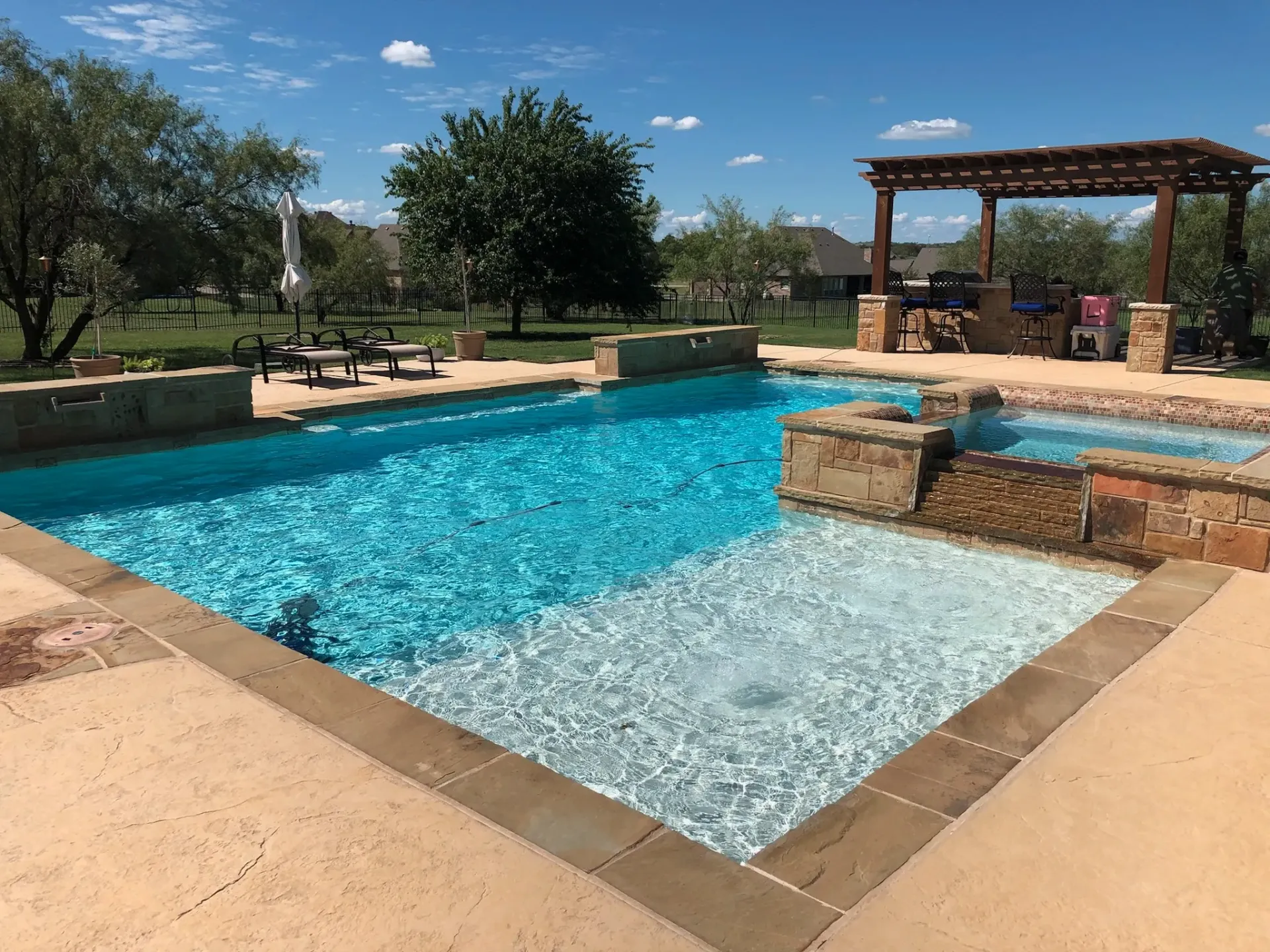A large swimming pool with a pergola in the background