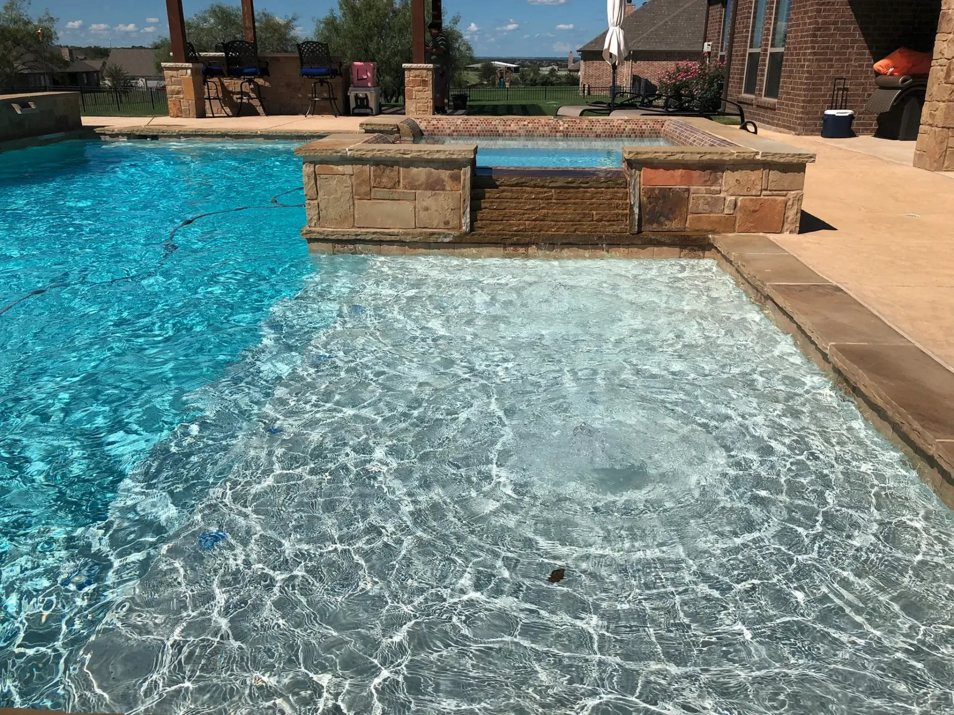 A large swimming pool with a hot tub in the middle of it.
