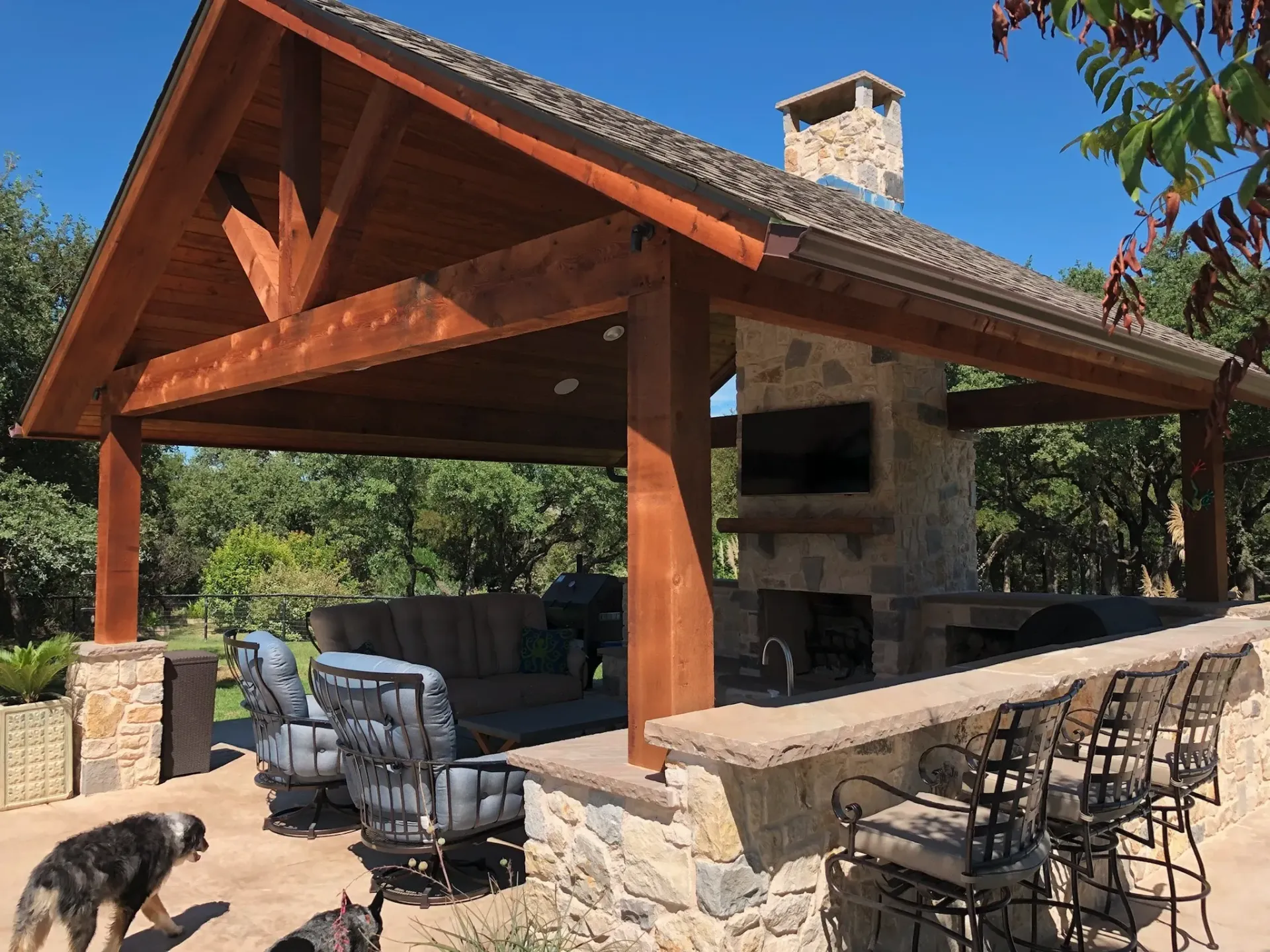 A dog is standing in front of a pavilion with a fireplace.