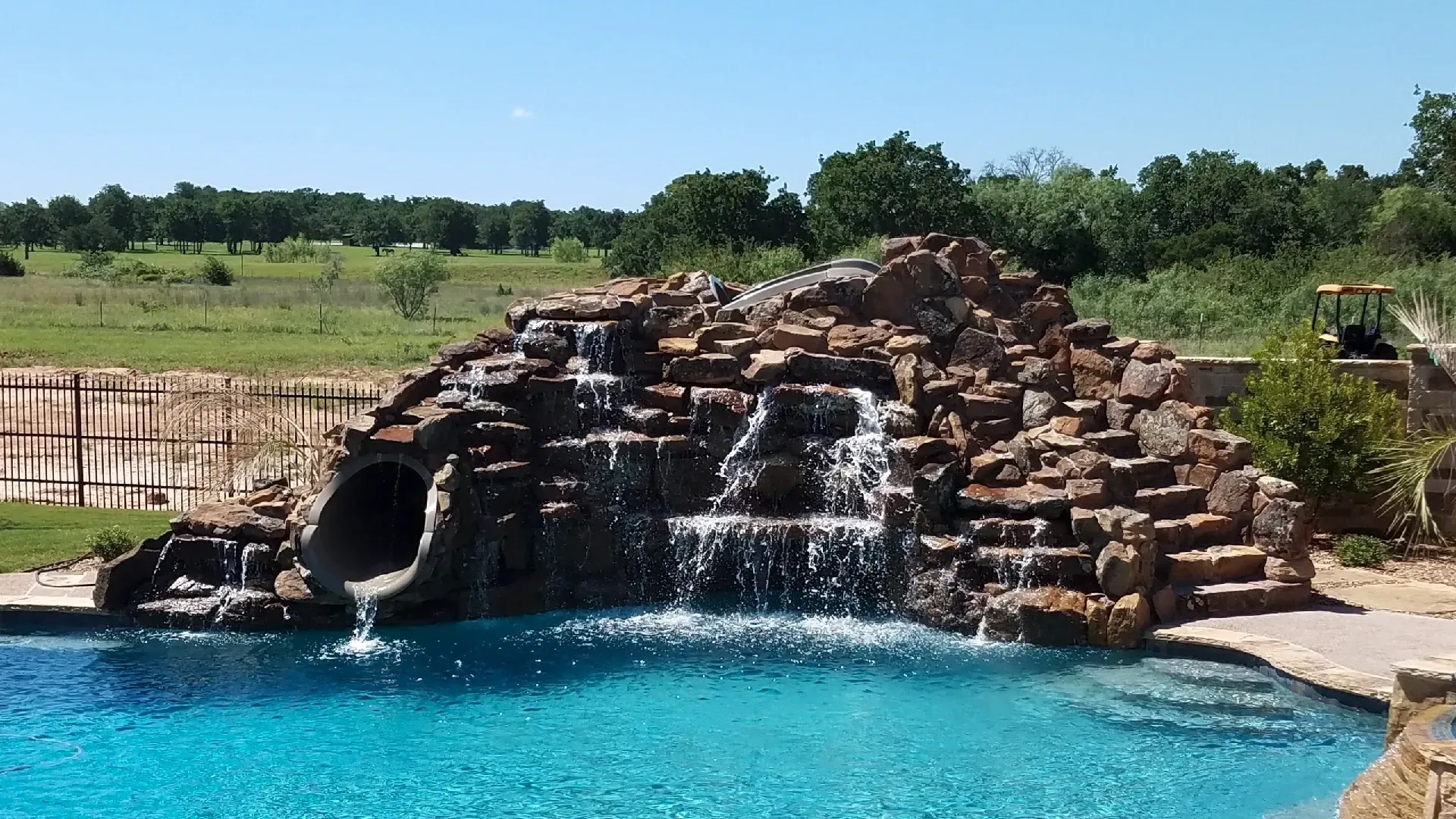 A large waterfall is in the middle of a swimming pool