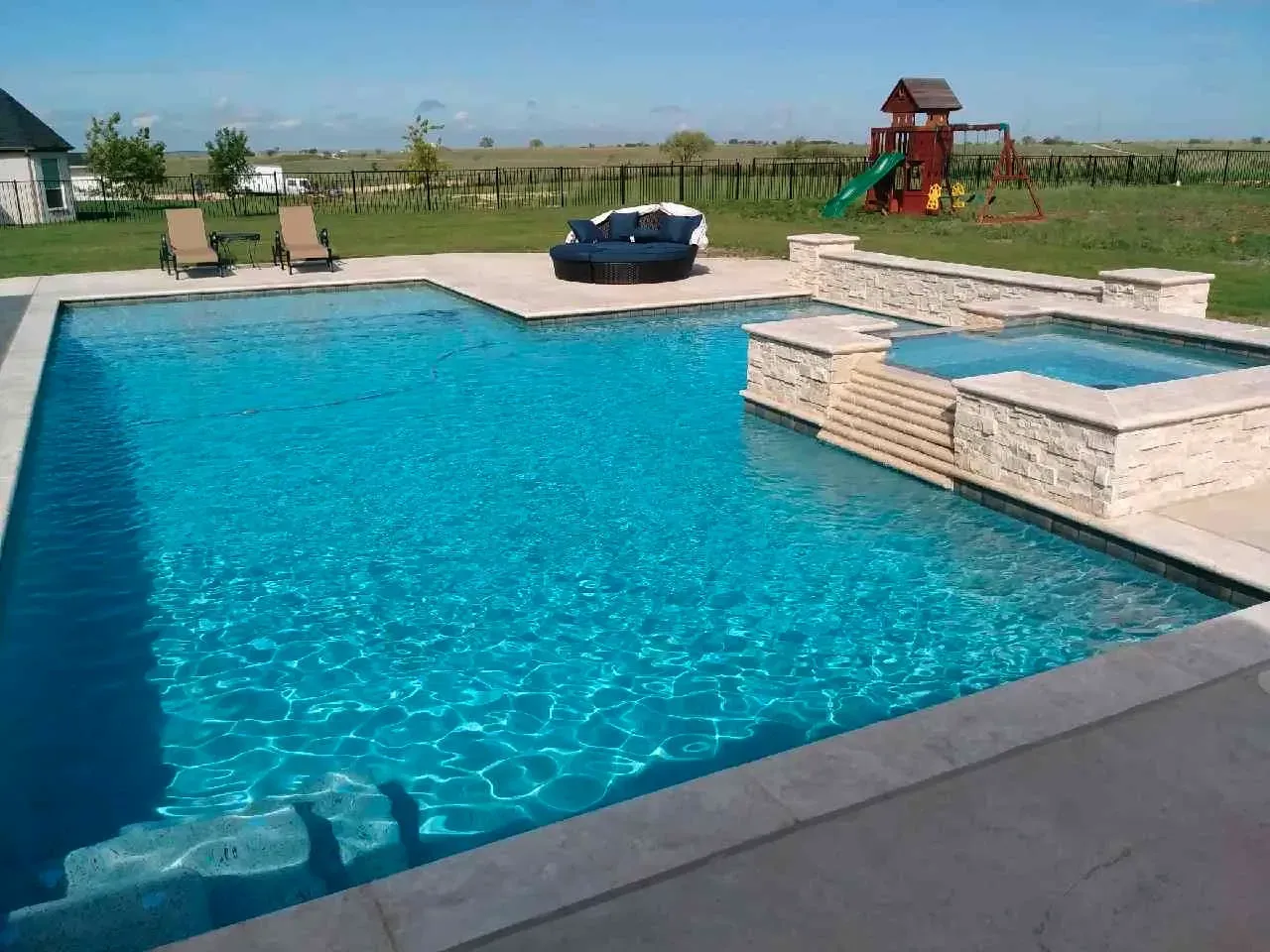 A large swimming pool with a playground in the background