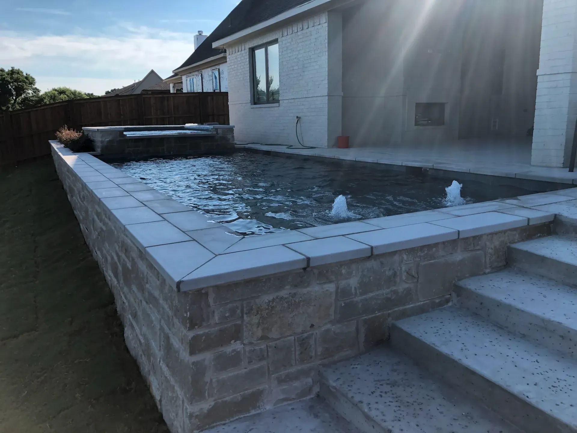 A large swimming pool with stairs leading up to it in front of a house.