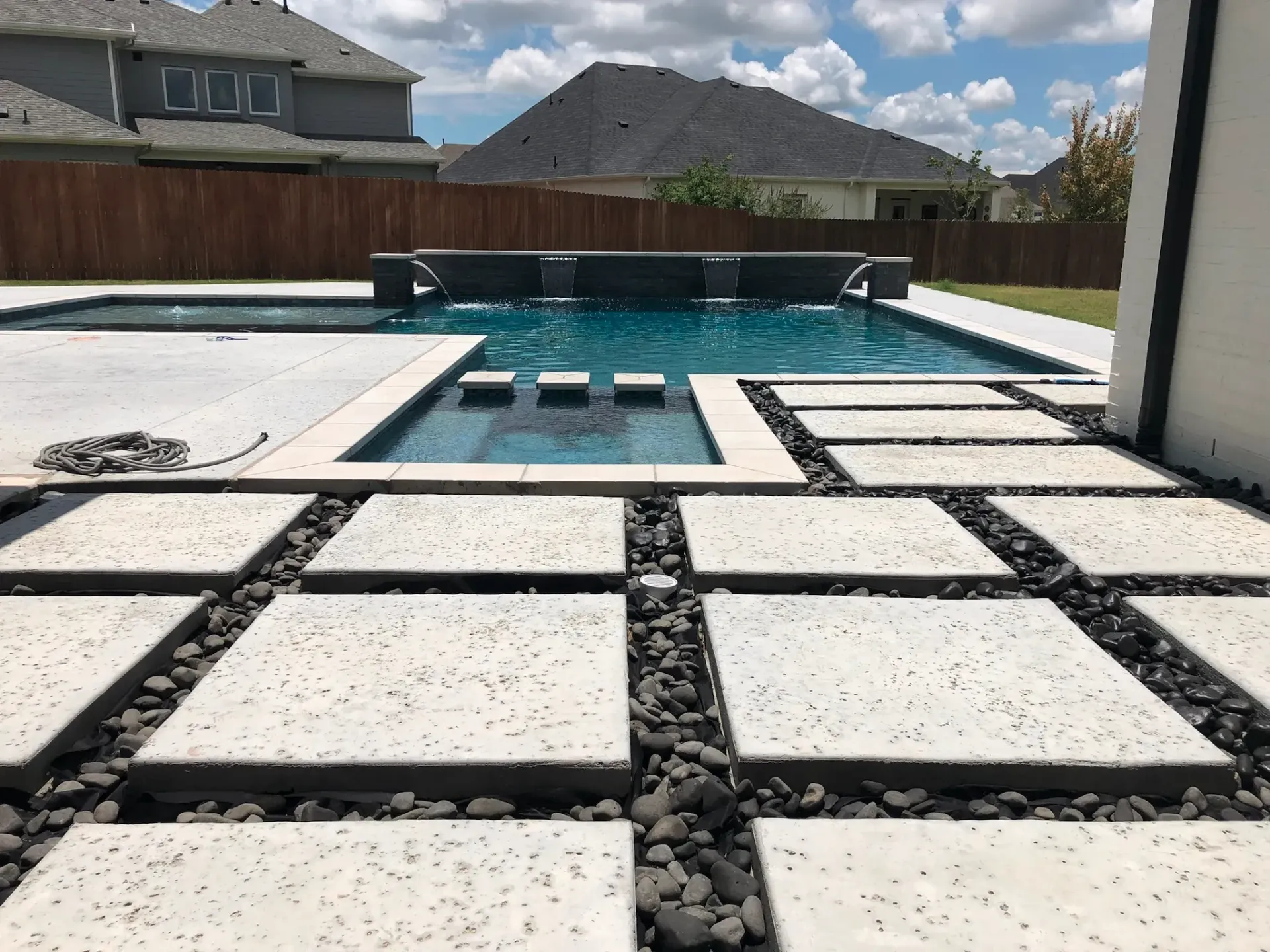 There is a large swimming pool in the backyard of a house.