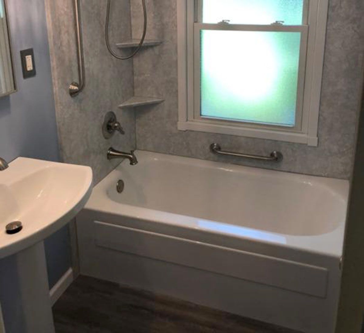 Bathroom with a bathtub, sink, window, and grab bars
