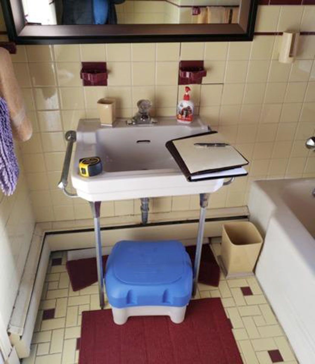 Bathroom with a pedestal sink, blue step stool, and retro tilework
