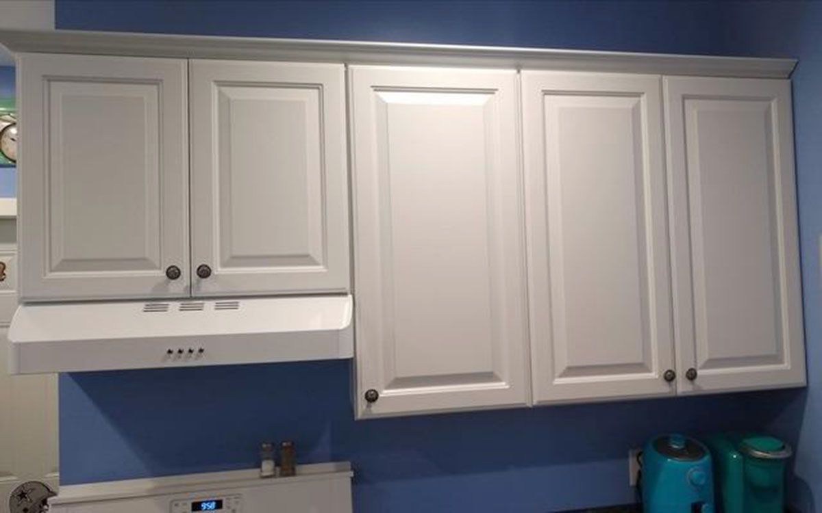 White kitchen cabinets with range hood against a blue wall
