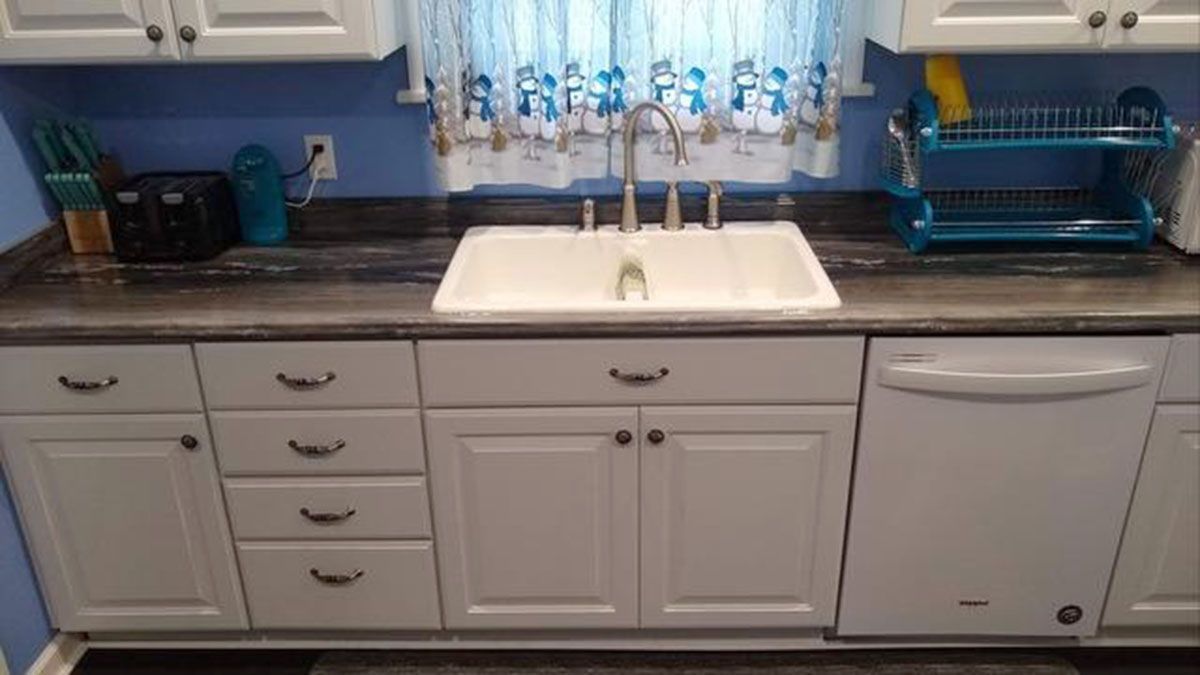 White kitchen with sink, cabinets, dishwasher, and blue backsplash