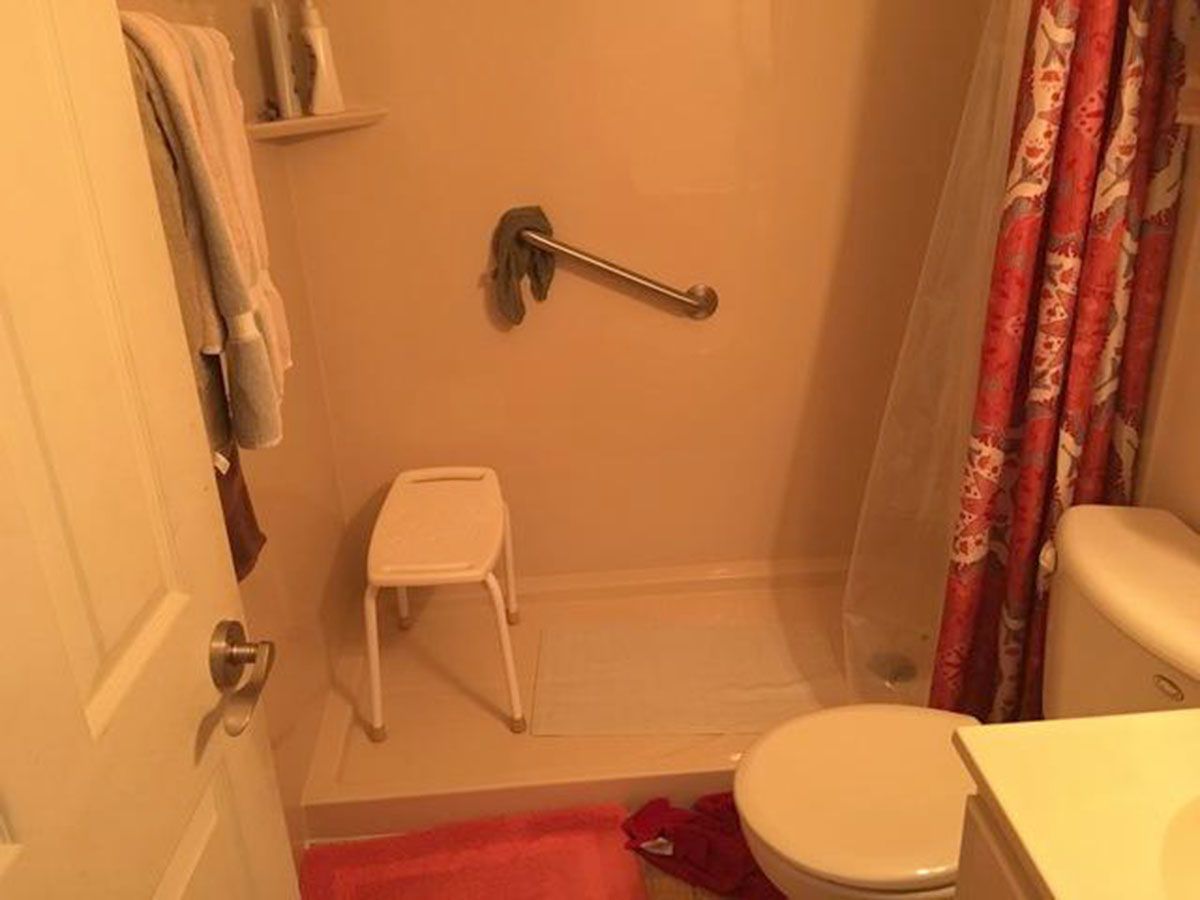 Bathroom with shower, grab bar, shower seat, red shower curtain, and toilet