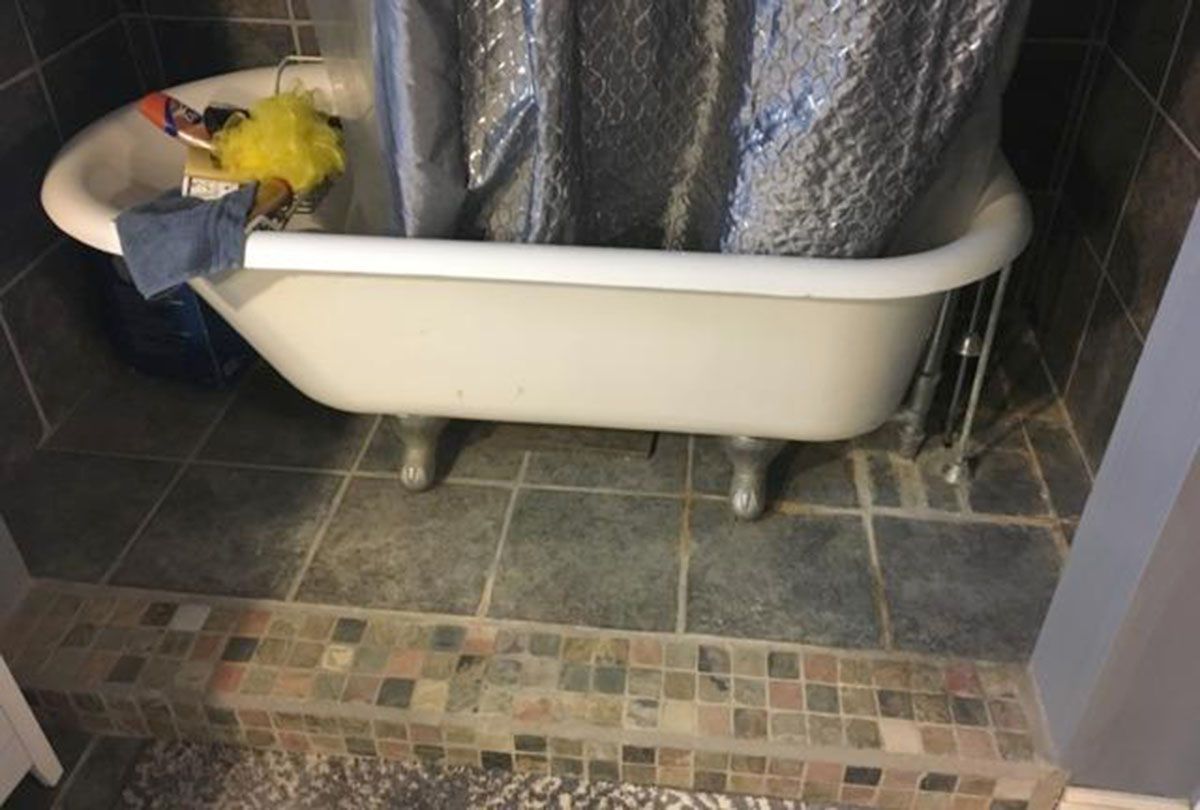Clawfoot bathtub in a tiled bathroom, shower curtain drawn