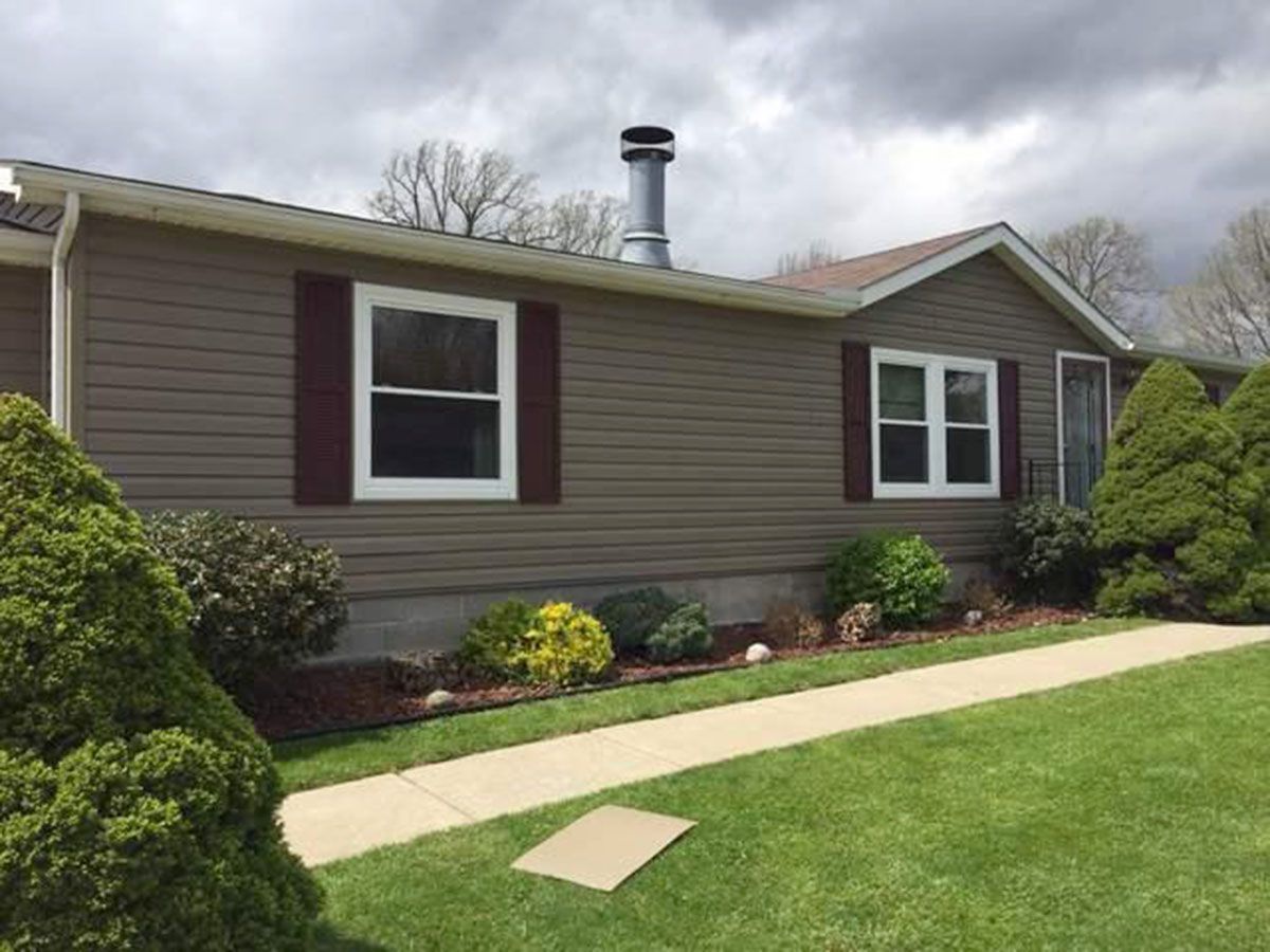 Tan house with white-framed windows, red shutters, and a chimney