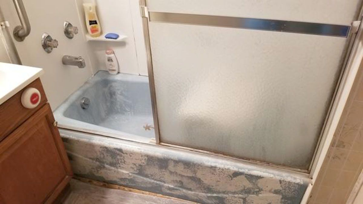 Blue bathtub with sliding glass door, soap and shampoo bottles visible