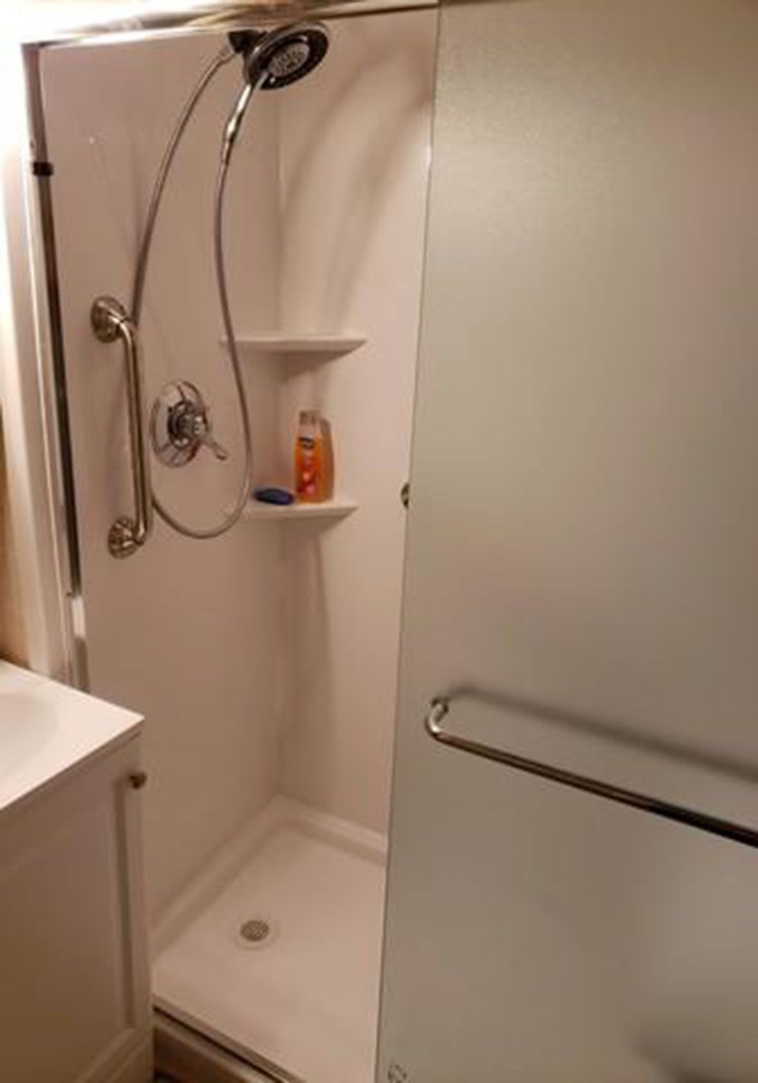 White shower stall with frosted glass door, shelves, and showerhead