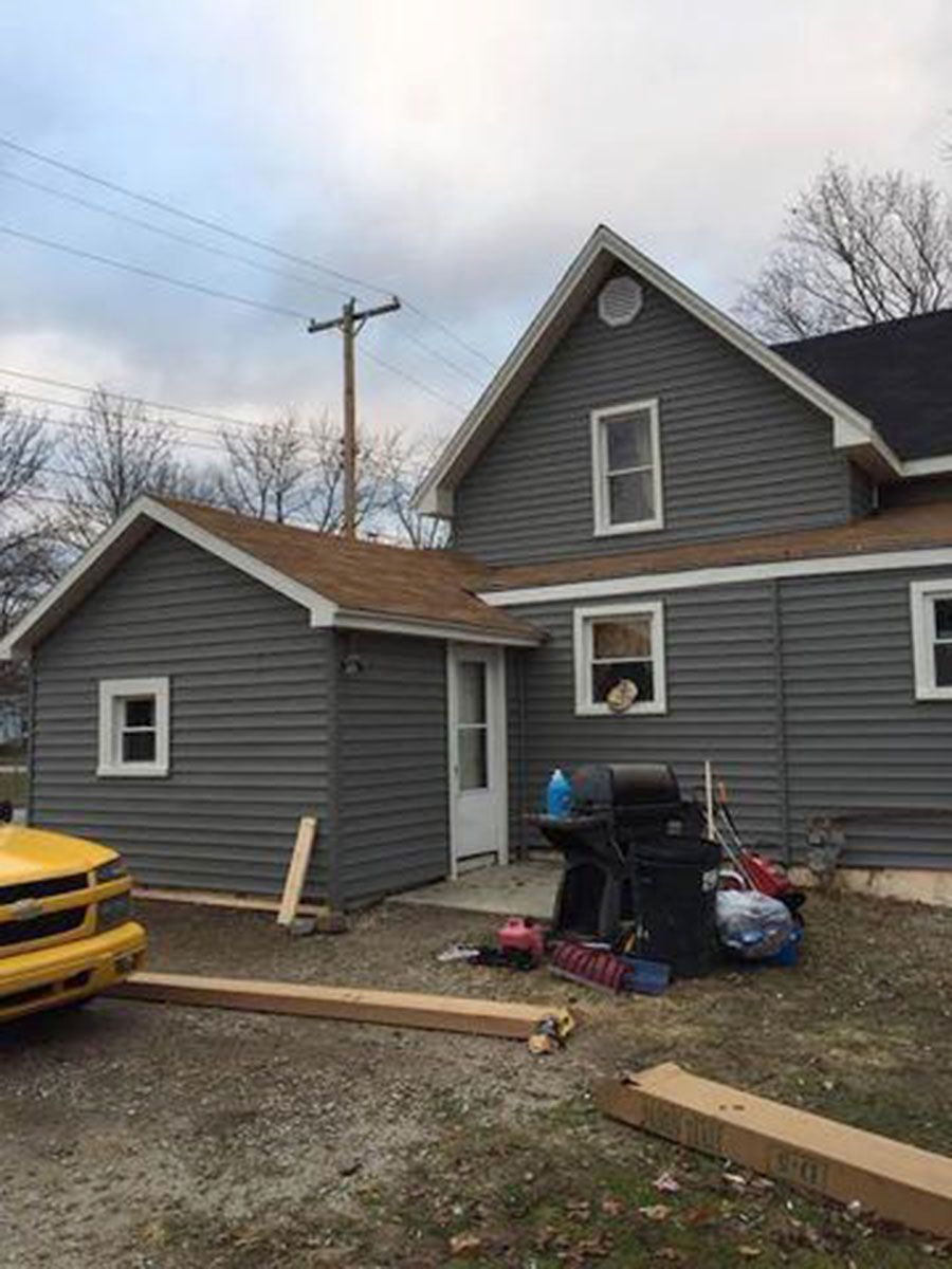 Gray house with attached garage, brown roof, white trim