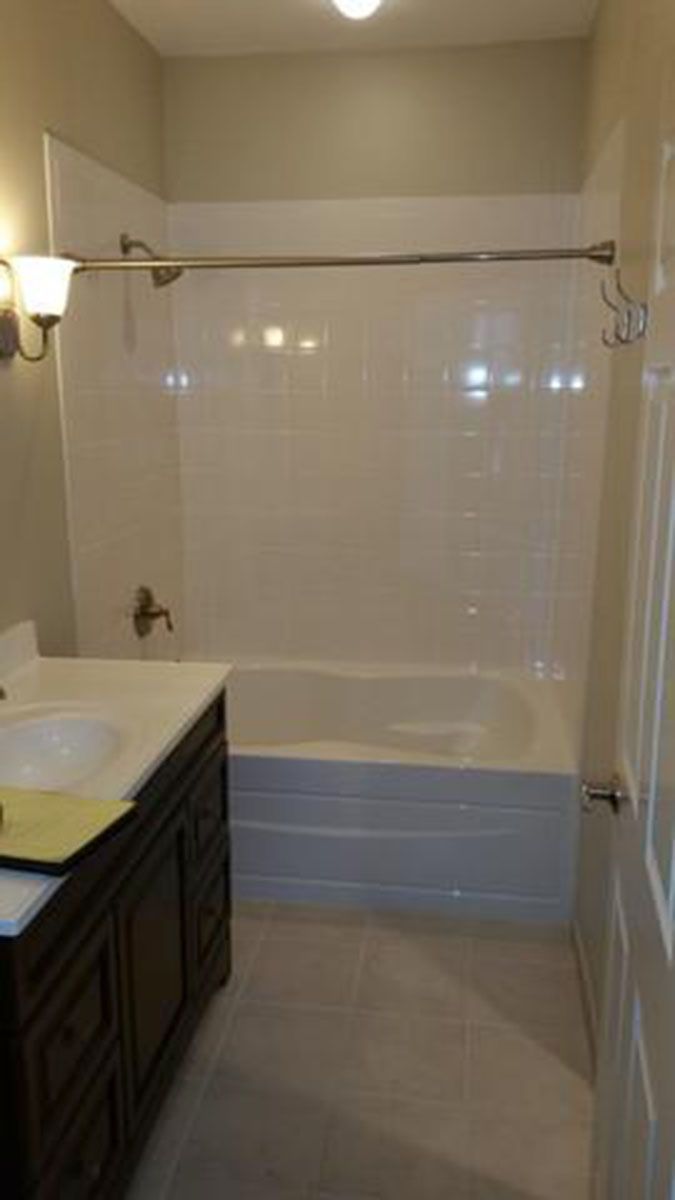 Bathroom with a white tub and walls, dark wood vanity, and a neutral-colored floor
