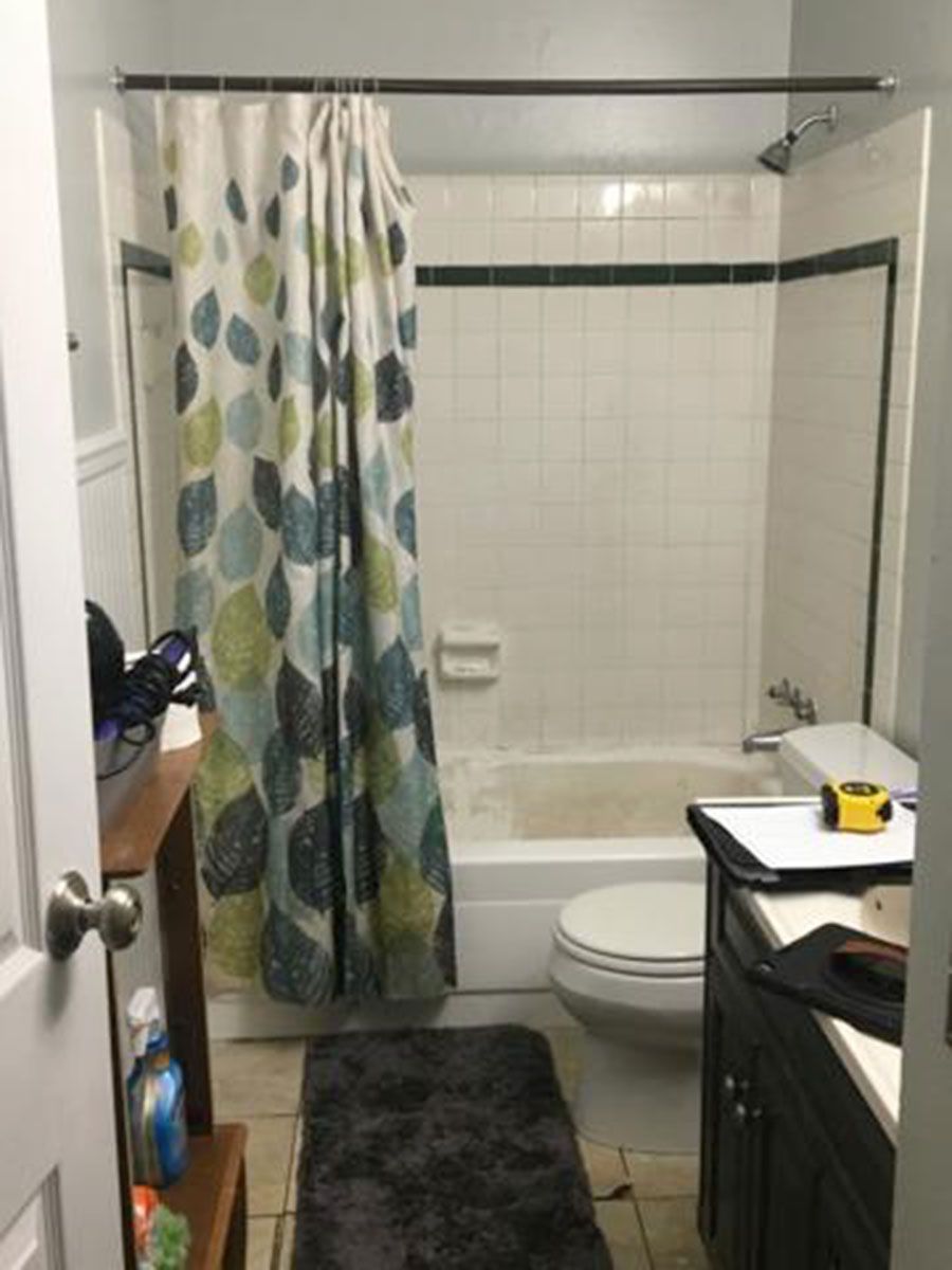 Small bathroom with a tub/shower, toilet, vanity, and a colorful leaf-patterned shower curtain