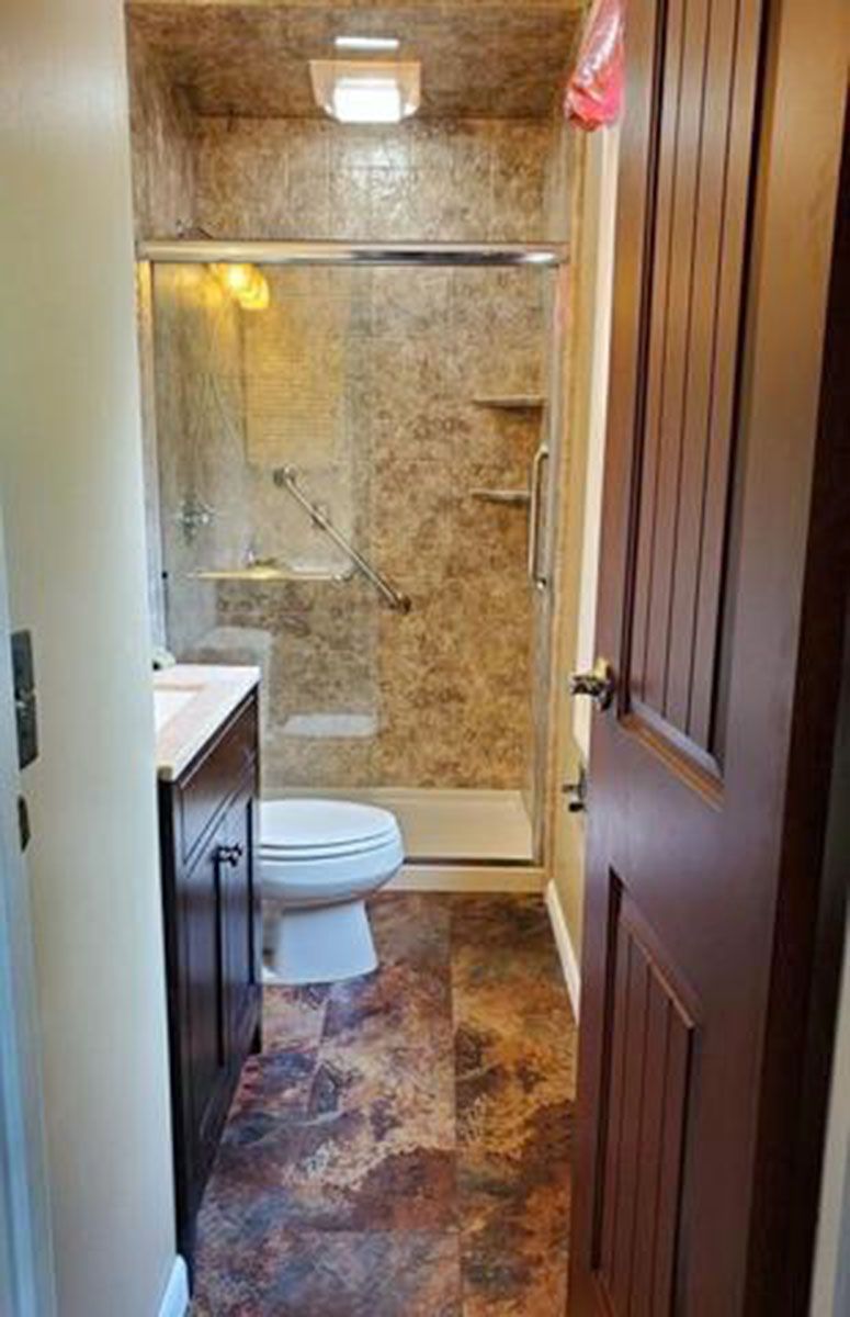 Bathroom interior with a shower, toilet, and vanity; wood-look flooring and brown walls