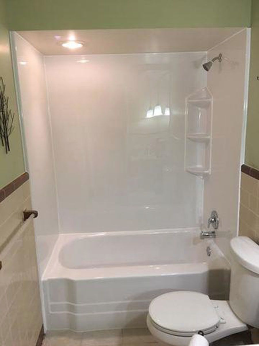 White alcove tub and shower unit in a bathroom, with a toilet on the right